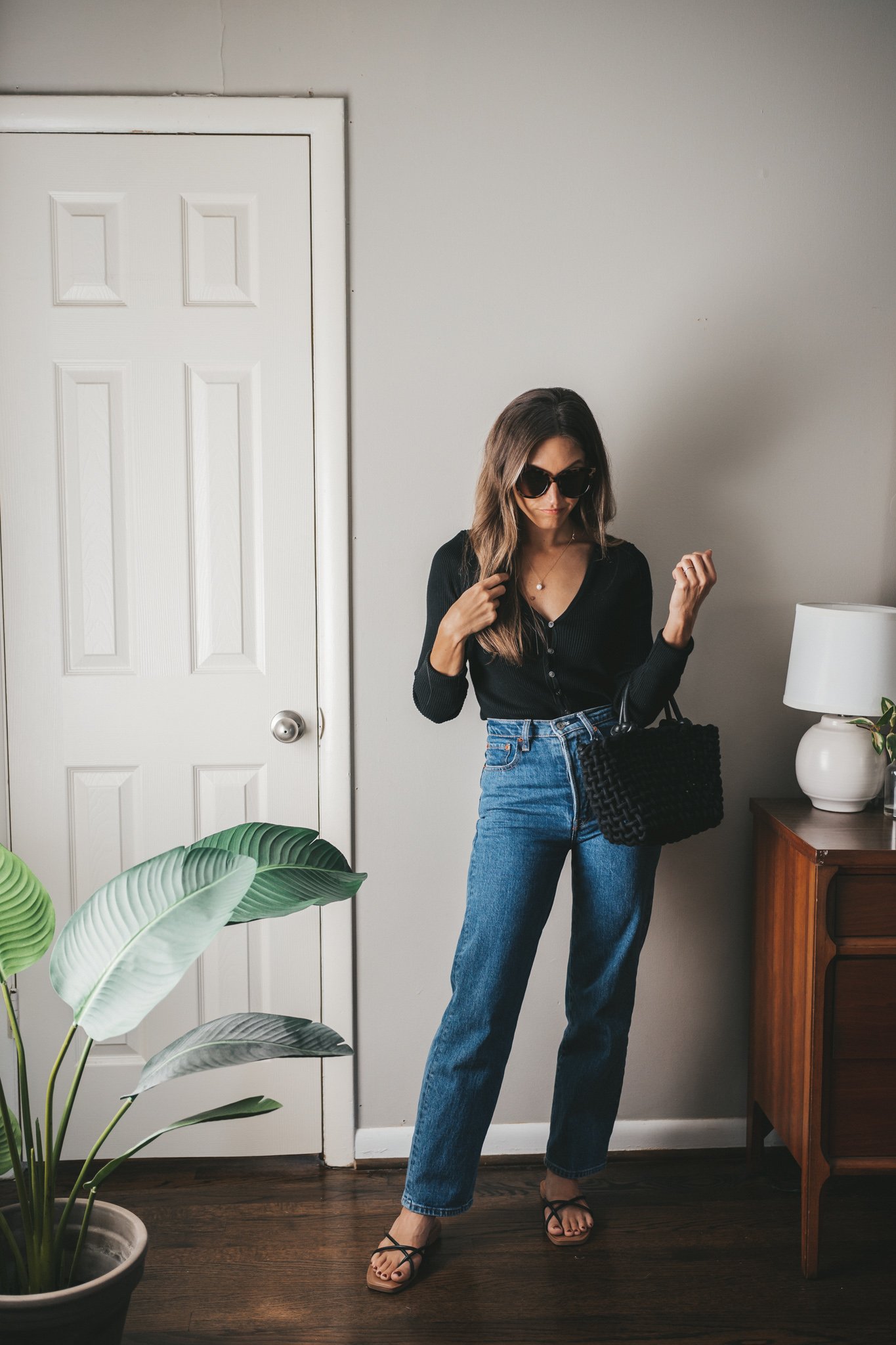 an early fall outfit with a cropped black cardigan, midwash high waisted jeans, and black strappy sandals