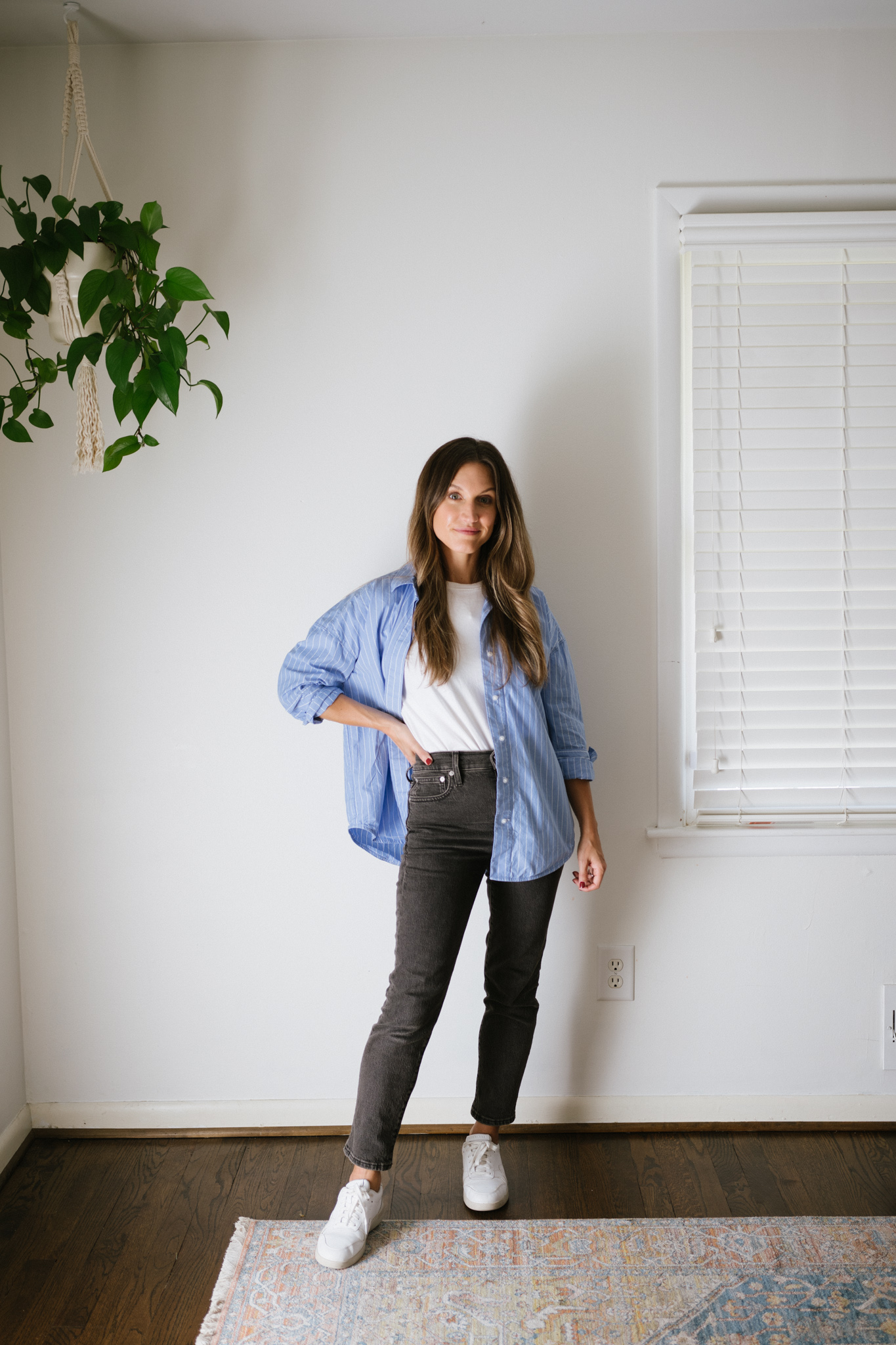 a minimalist outfit for fall with a white tee, blue button down, black denim, and white sneakers