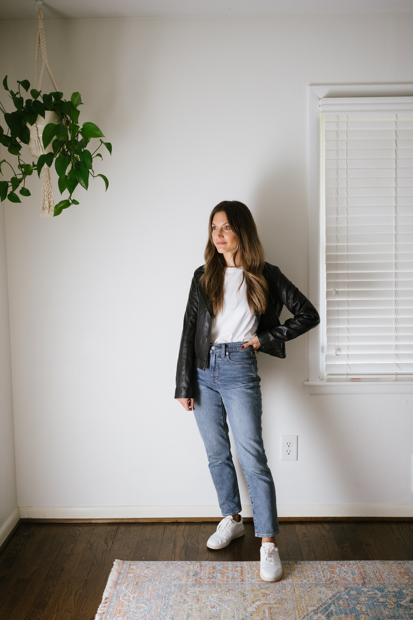 a classic fall outfit with a white tee, black leather jacket, mid-wash denim, and white sneakers