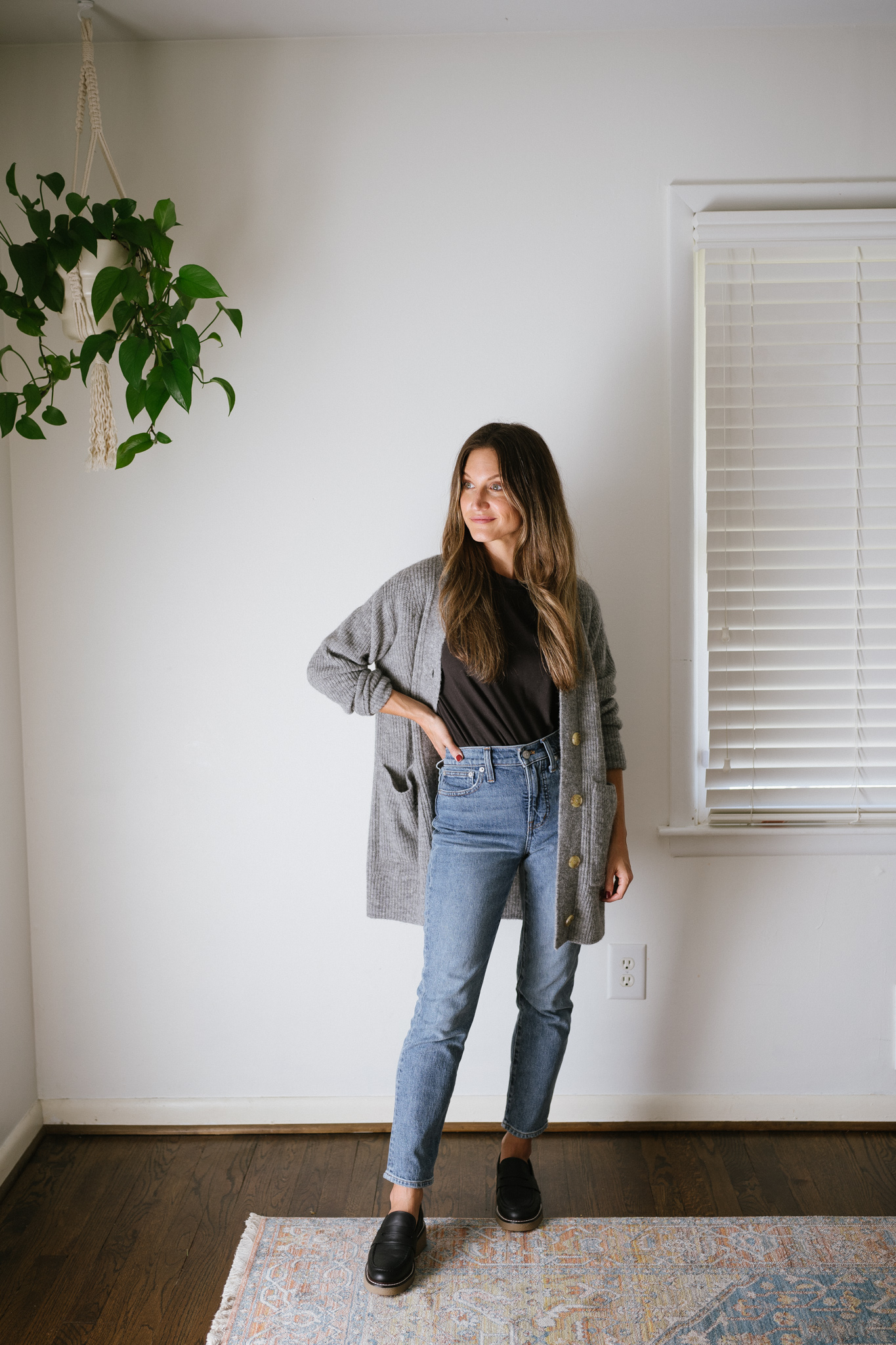 a minimalist outfit for fall with a black tee, gray cardigan, mid-wash denim, and black loafers