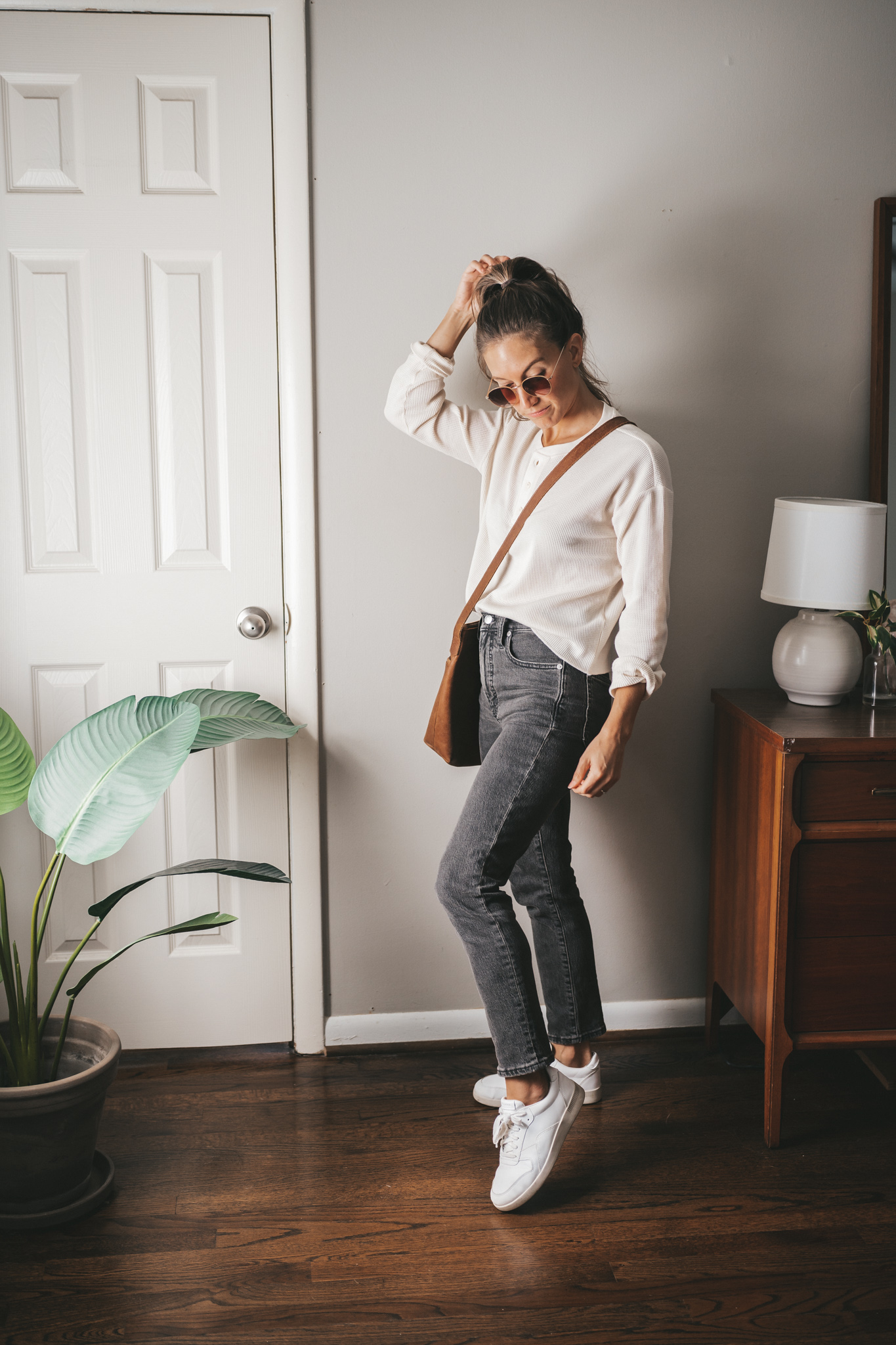 a weekend outfit with a cream colored henley, washed black denim, and white sneakers