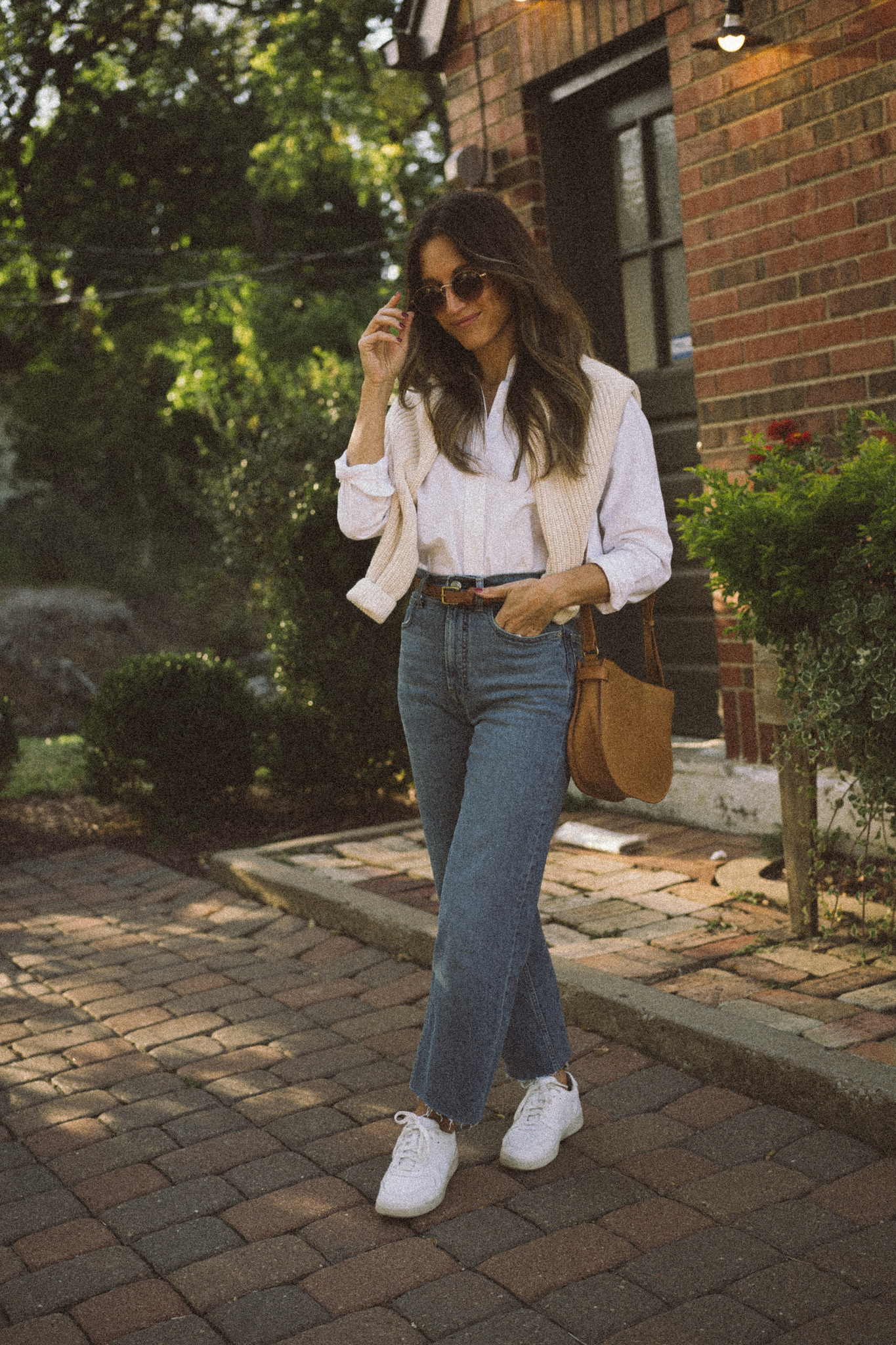 my fall uniform featuring a white button down, cream sweater over the shoulders, straight leg denim, and white sneakers