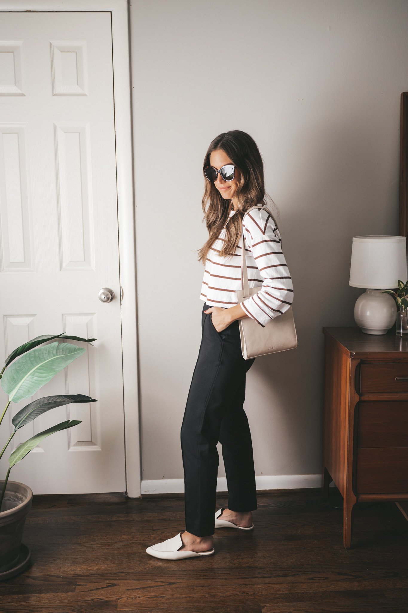 casual chic outfit idea with a striped cropped tee, black pants, and white mules