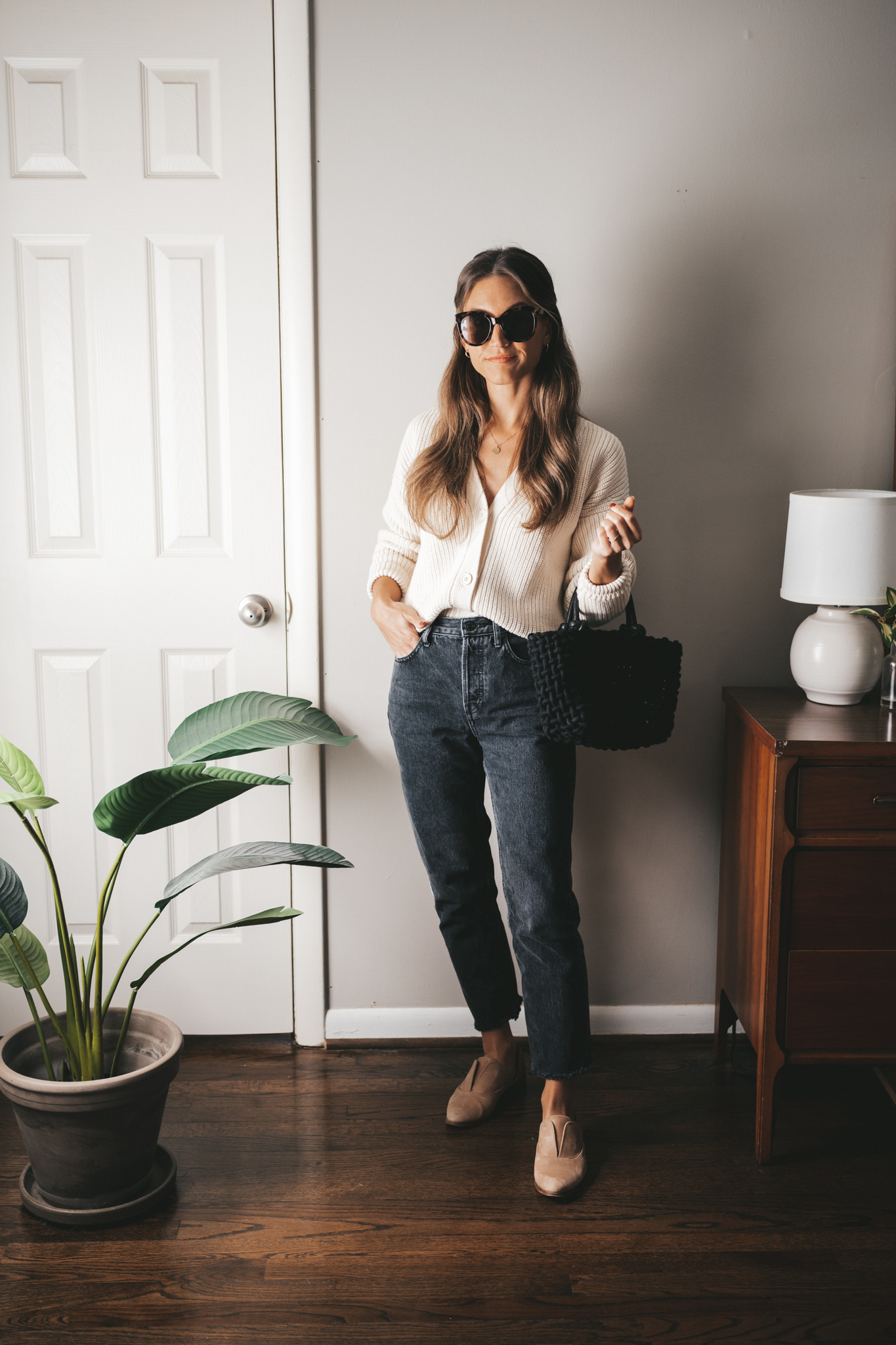 casual outfit with a cream colored button front cardigan, black denim, and brown oxfords
