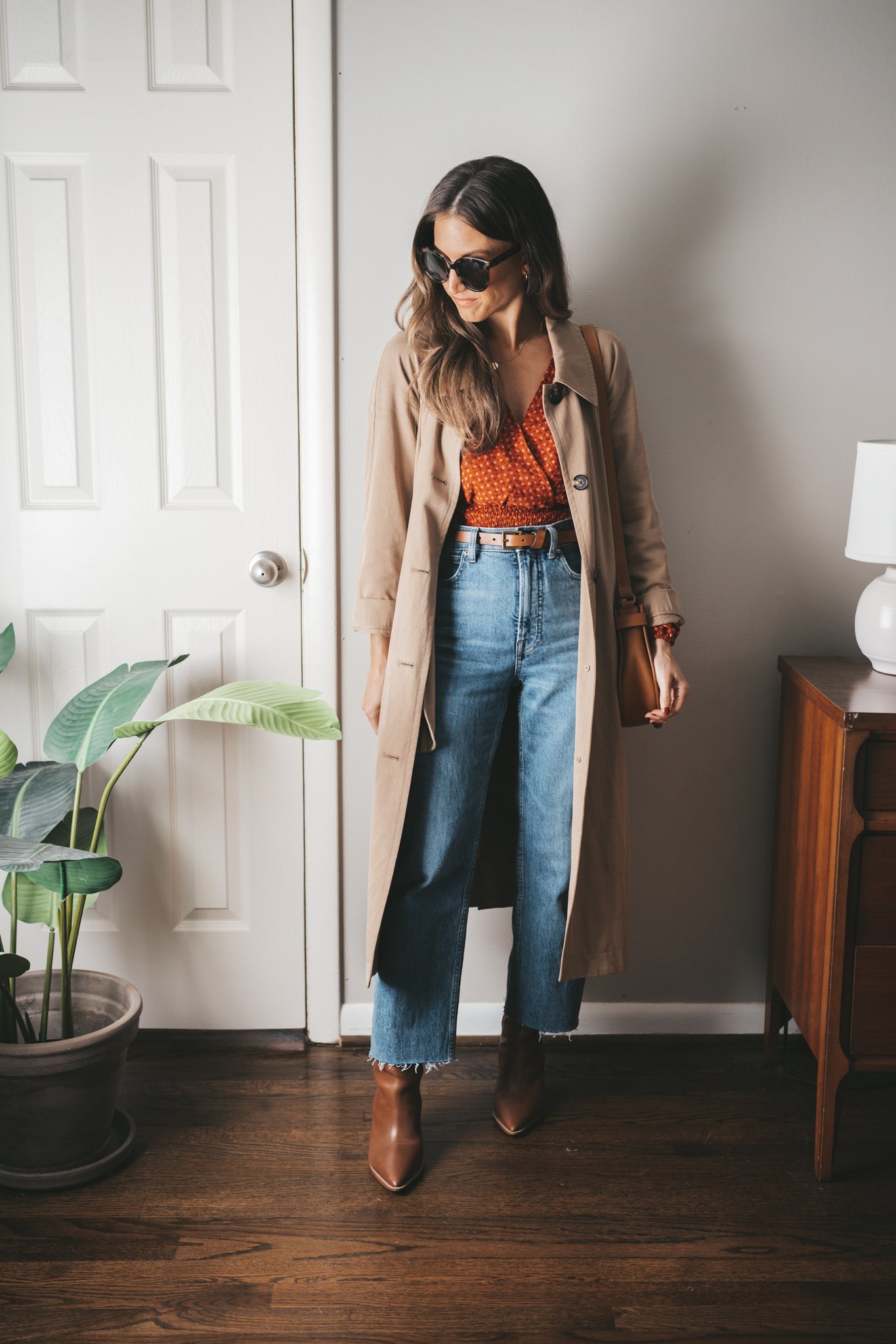 casual chic outfit with a red blouse, trench coat, straight denim, and brown ankle boots