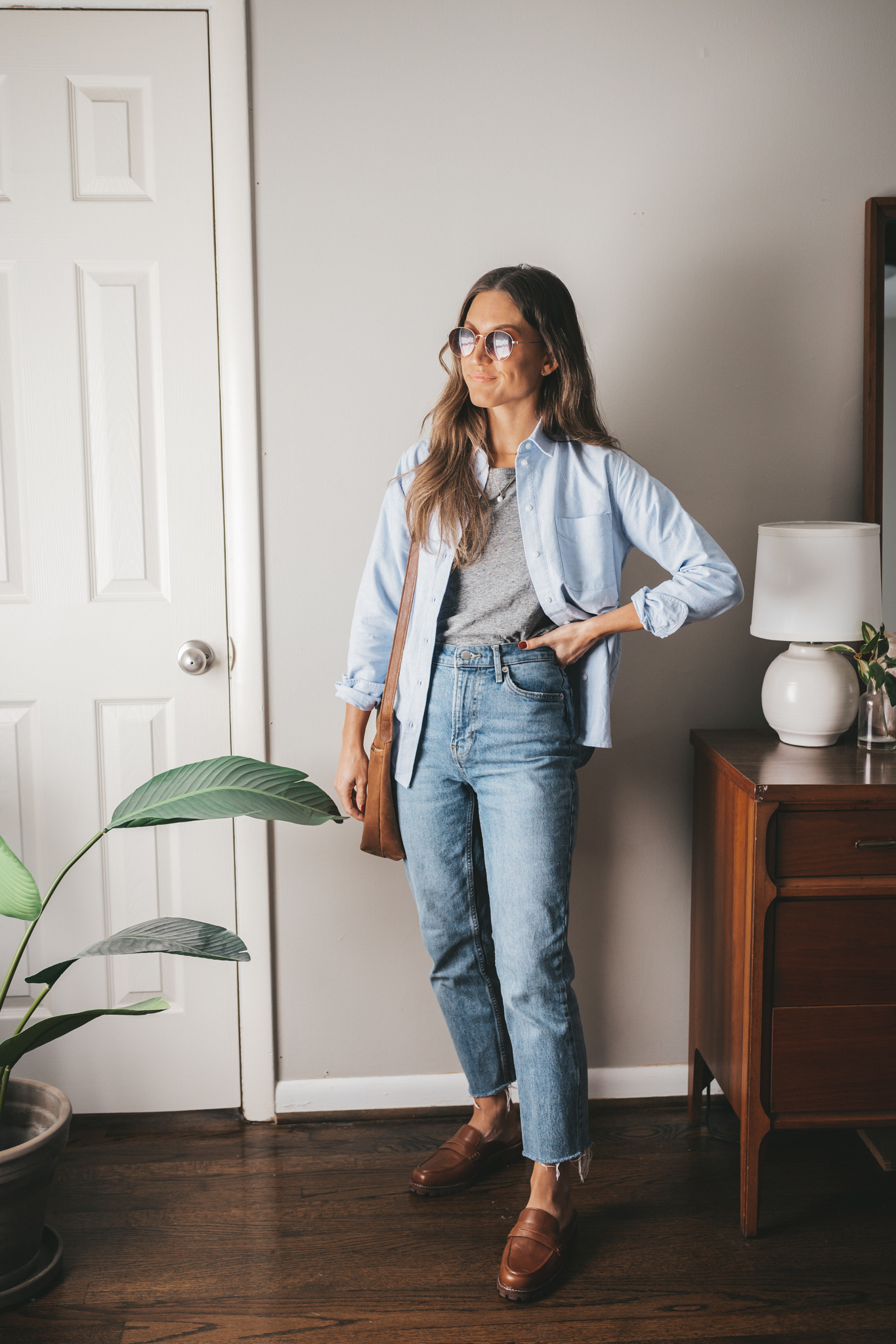 casual chic outfit with a gray tee, light blue button down worn unbuttoned, mid-wash denim and brown loafer mules