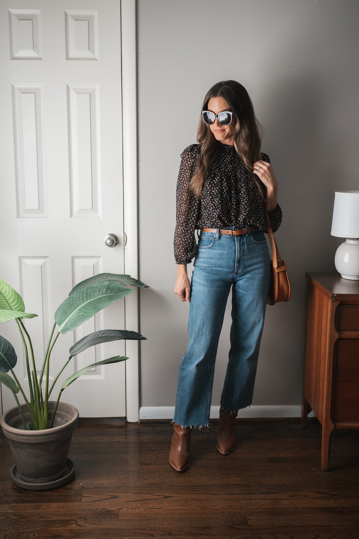 fall outfit idea with denim, a black patterned blouse and brown boots