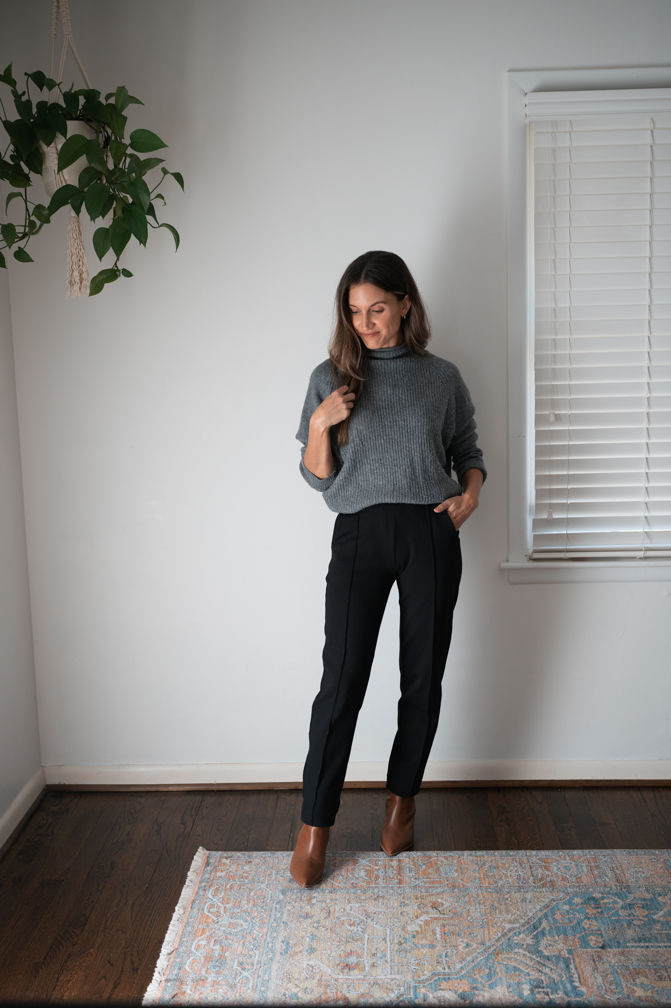 black pants outfit idea with a gray mockneck sweater and brown ankle boots
