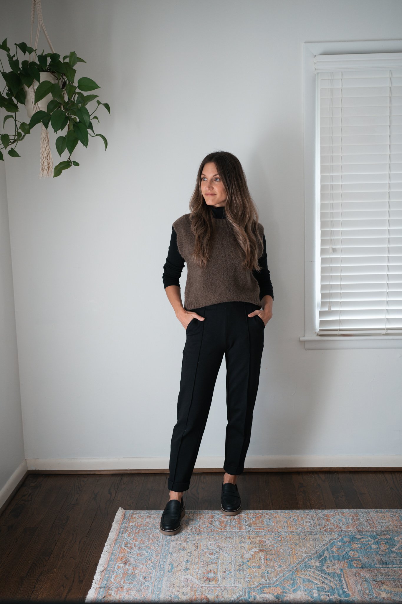 ways to style black pants for fall with a black turtleneck, brown sweater vest, and black chunky loafers