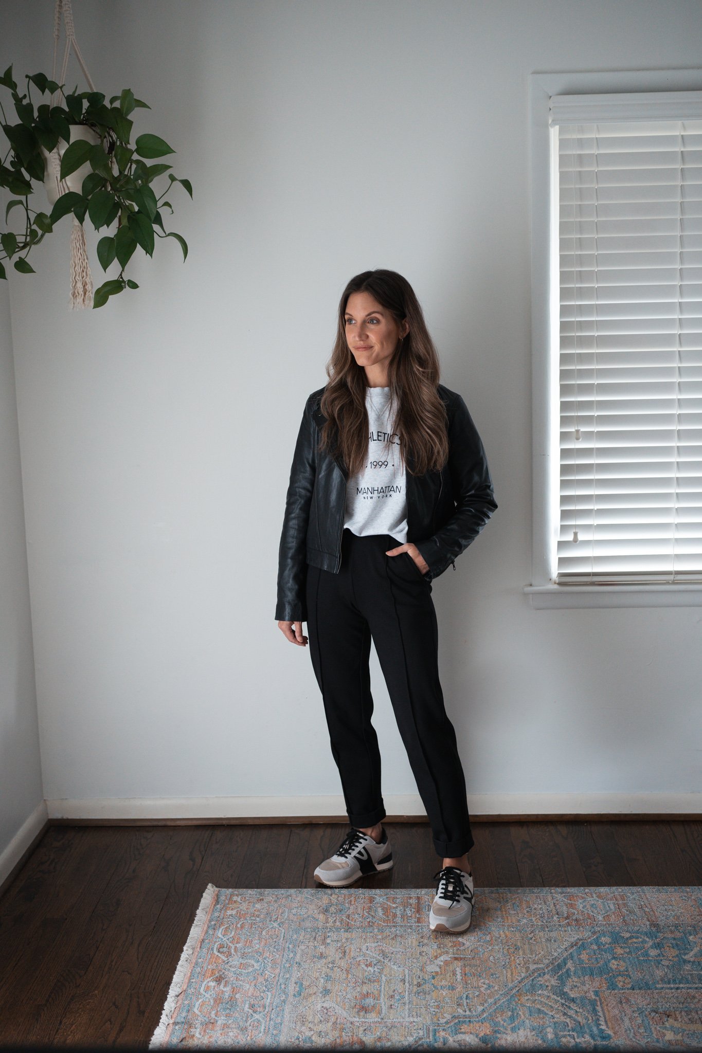 ways to style black pants with a graphic sweatshirt, leather jacket, and casual sneakers