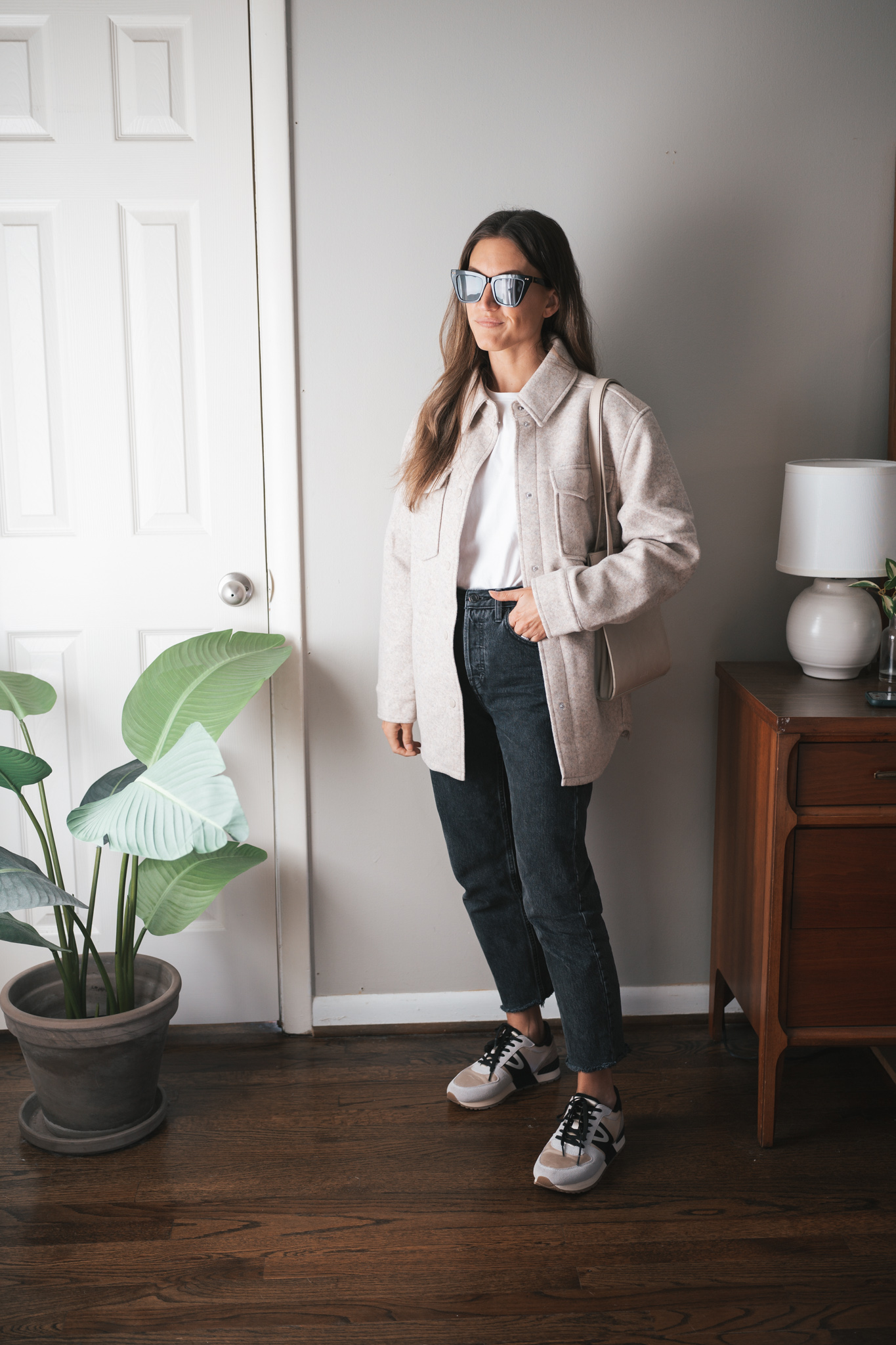 ashley wearing a white tee, beige shacket, black denim, and casual sneakers