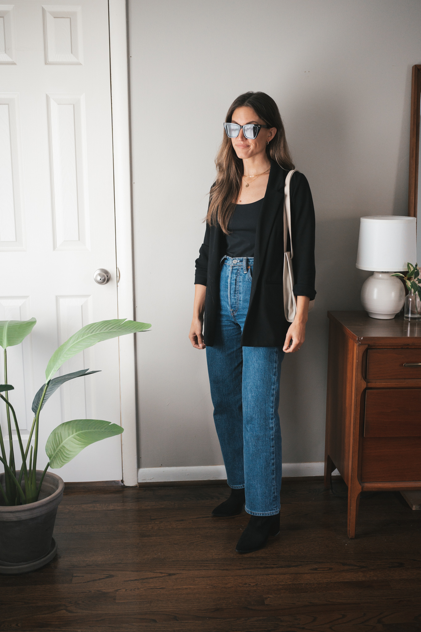 fall outfit idea with denim, a black bodysuit tank, black blazer, and black boots