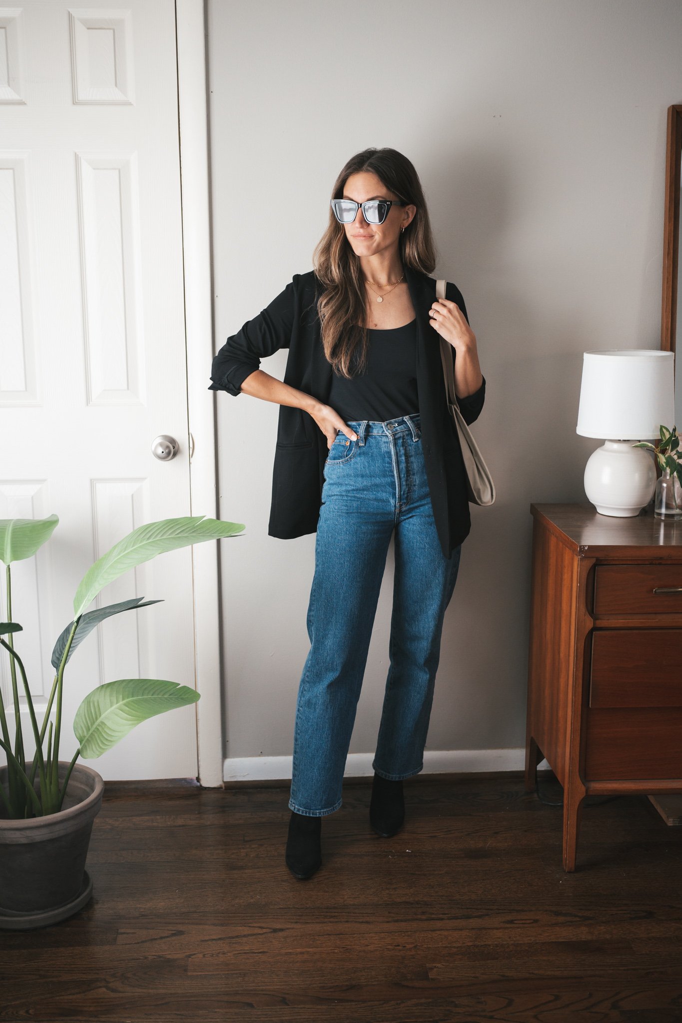 fall outfit idea with denim, a black bodysuit tank, black blazer, and black boots