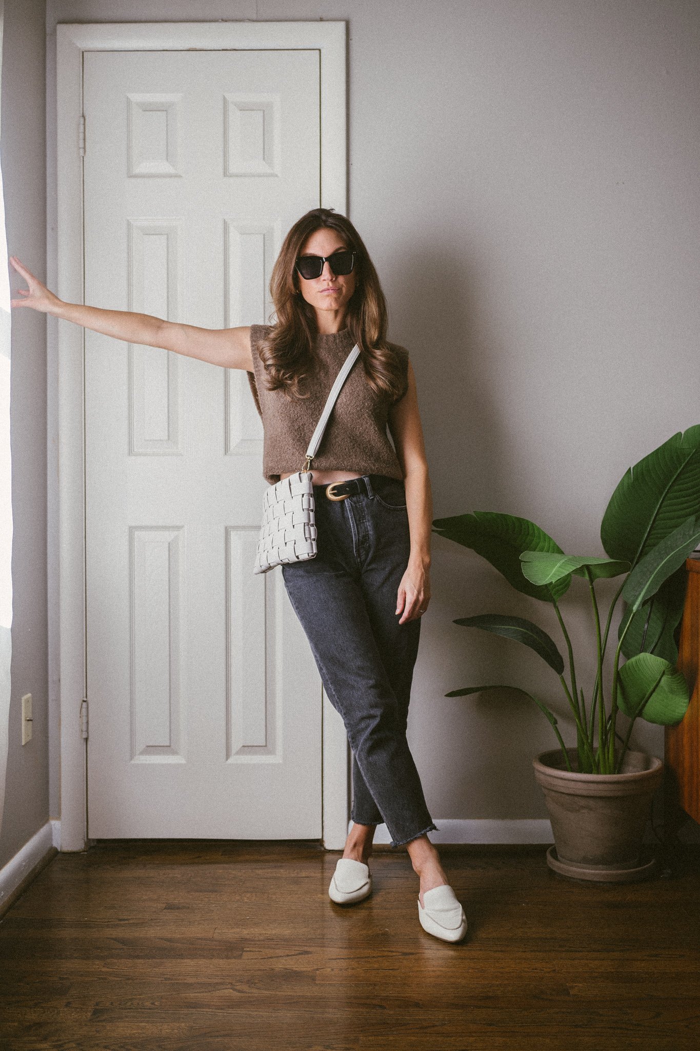 casual fall outfit idea with a brown sweater vest, black denim, and white mules