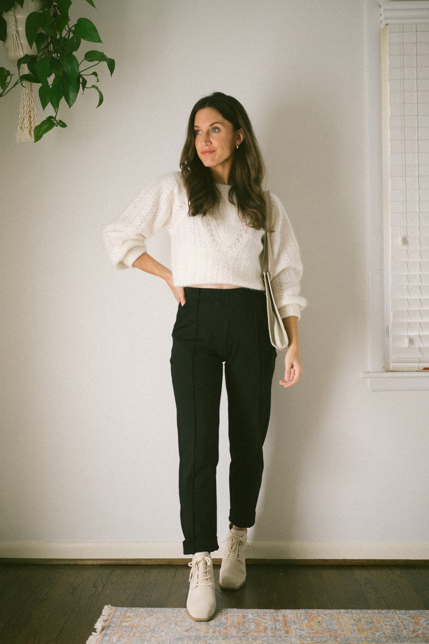ashley wearing a white sweater, black pants, and gray ankle boots