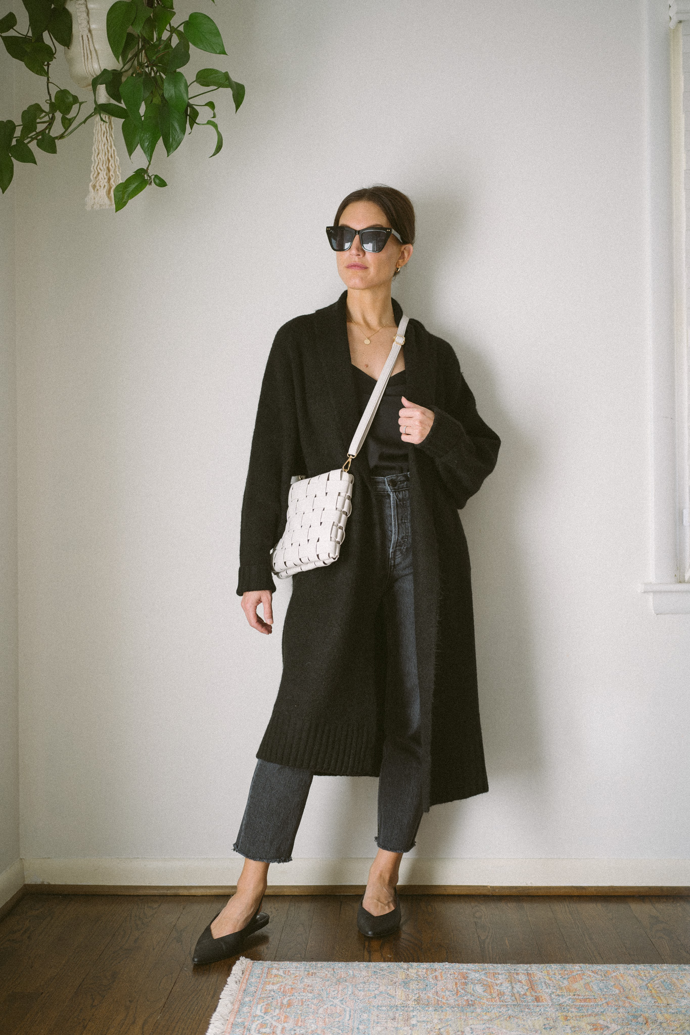 ashley wearing a black silk cami, black sweater coat, black denim, and black slingback flats