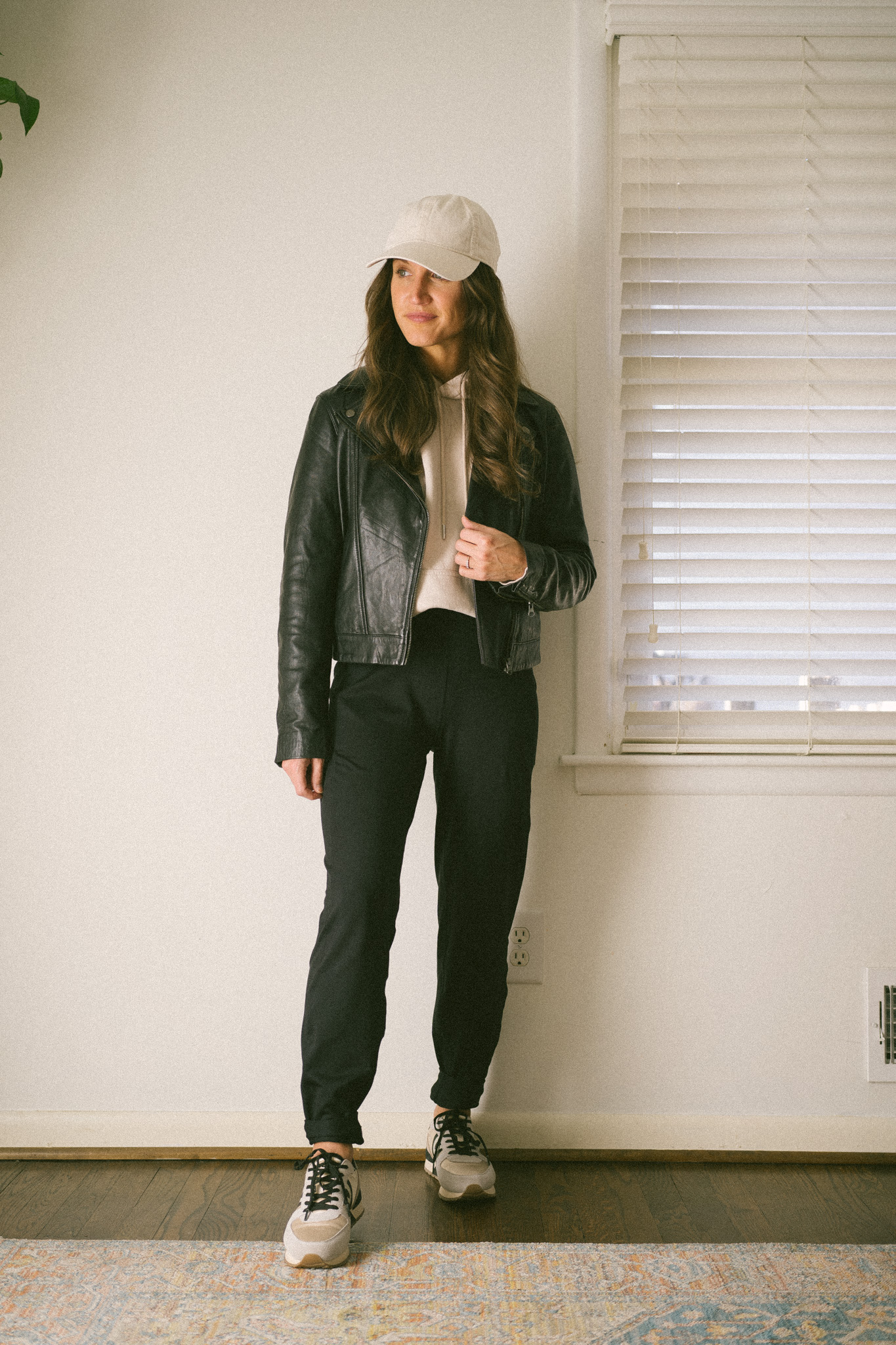 casual fall outfit with a taupe hoodie, leather jacket, black joggers, and casual sneakers