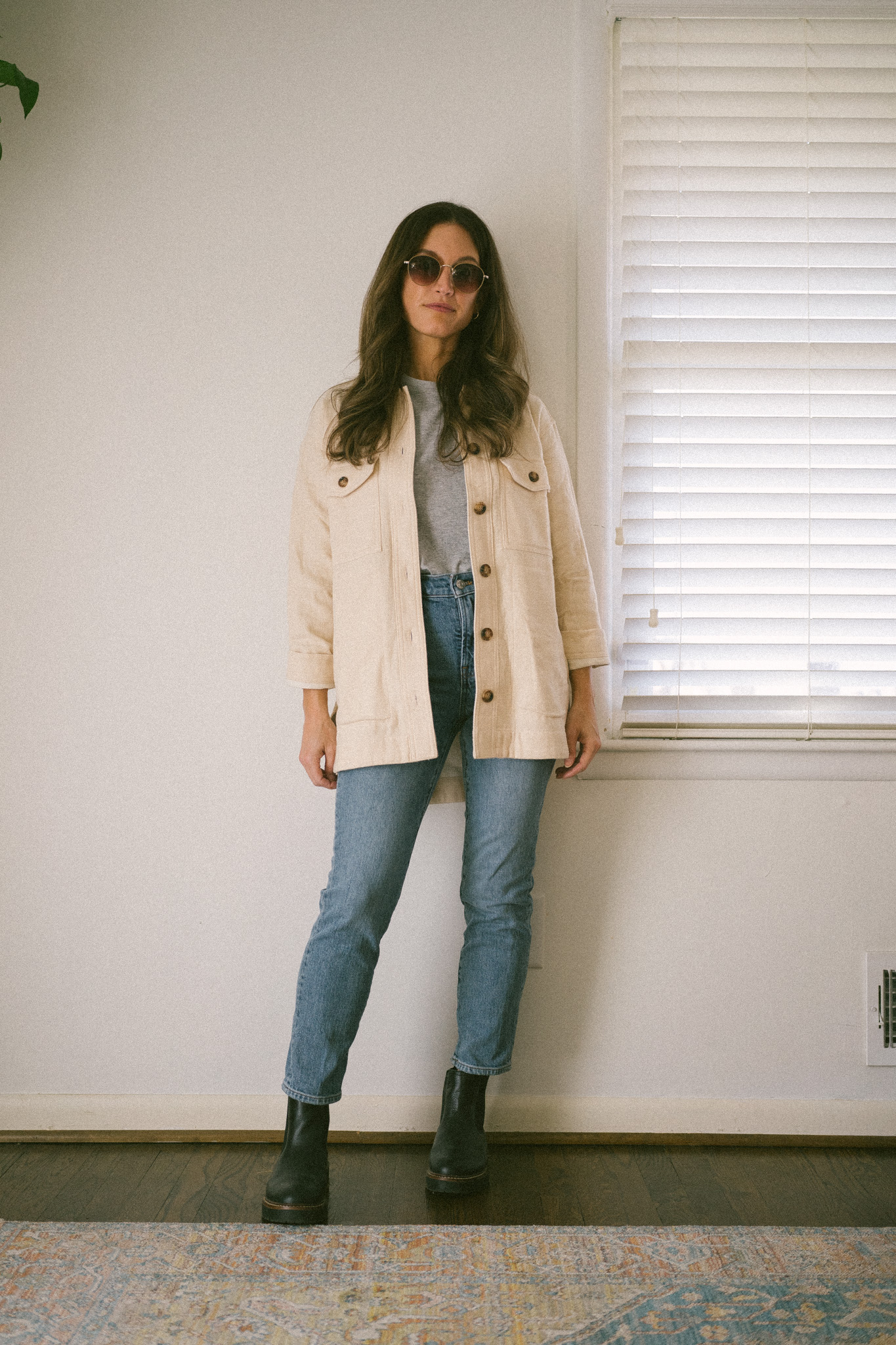 weekend outfit with a gray tee, cream shacket, medium wash denim, and black chelsea boots