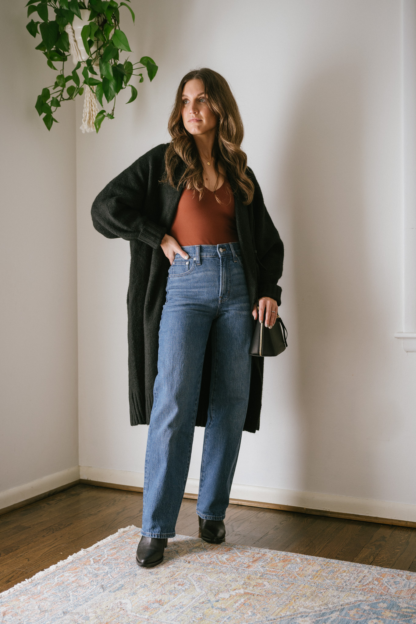thanksgiving outfit idea with a brown bodysuit, oversized black long cardigan, wide leg jeans, and black ankle boots