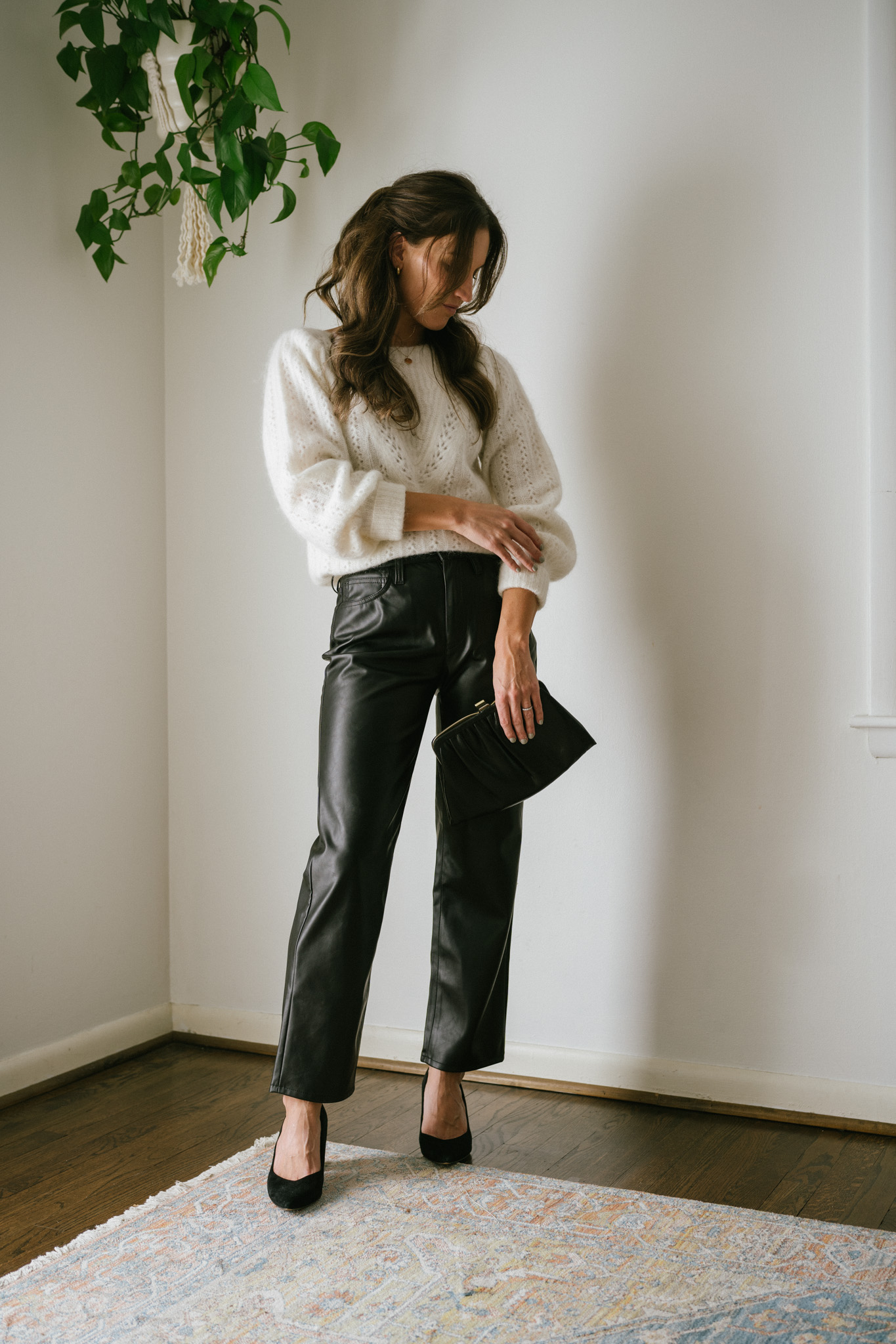 outfit idea for Thanksgiving with a white sweater, faux leather straight pants, black pumps, and a black clutch bag