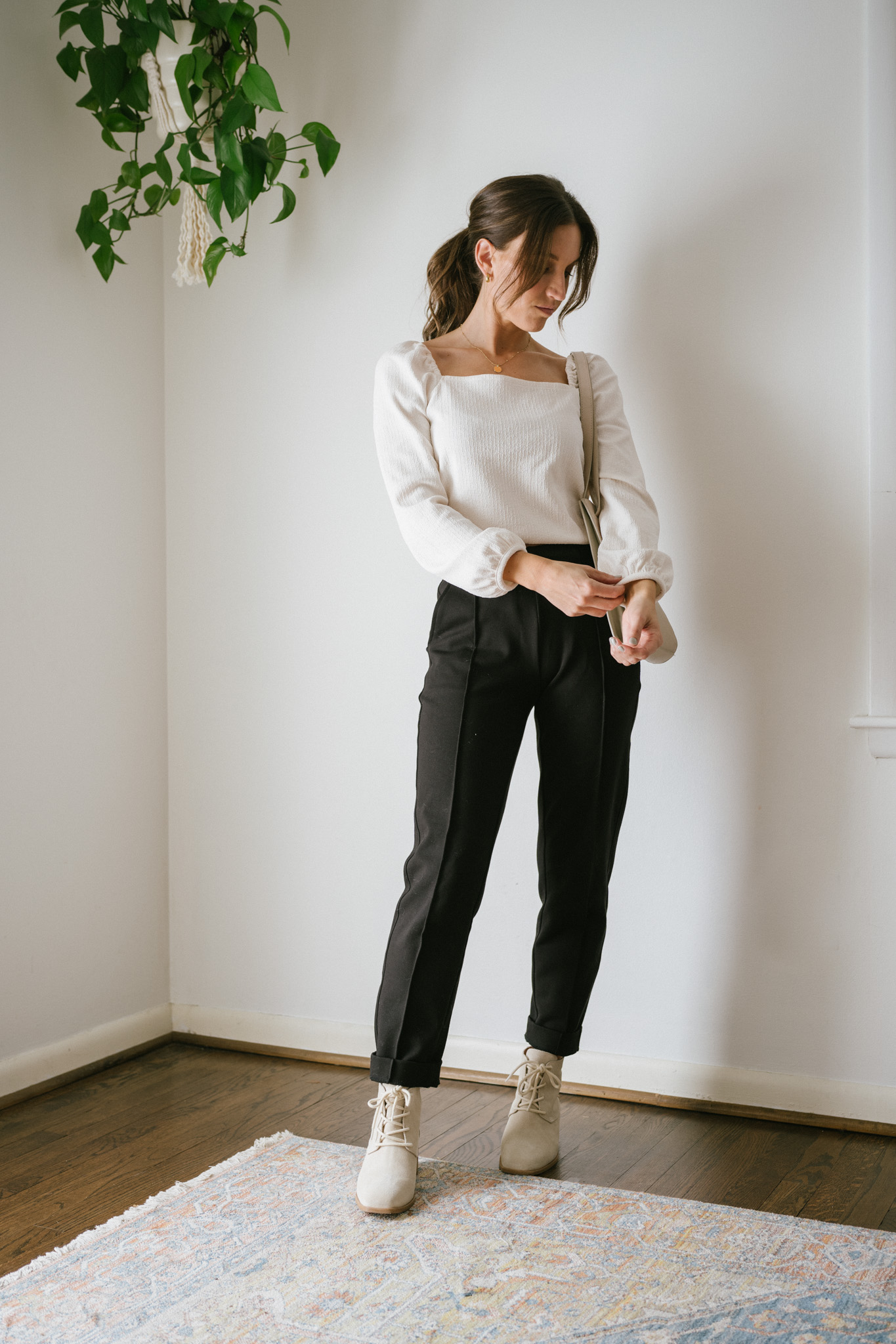 ashley wearing a white puff sleeve top, black pants, and light gray ankle boots
