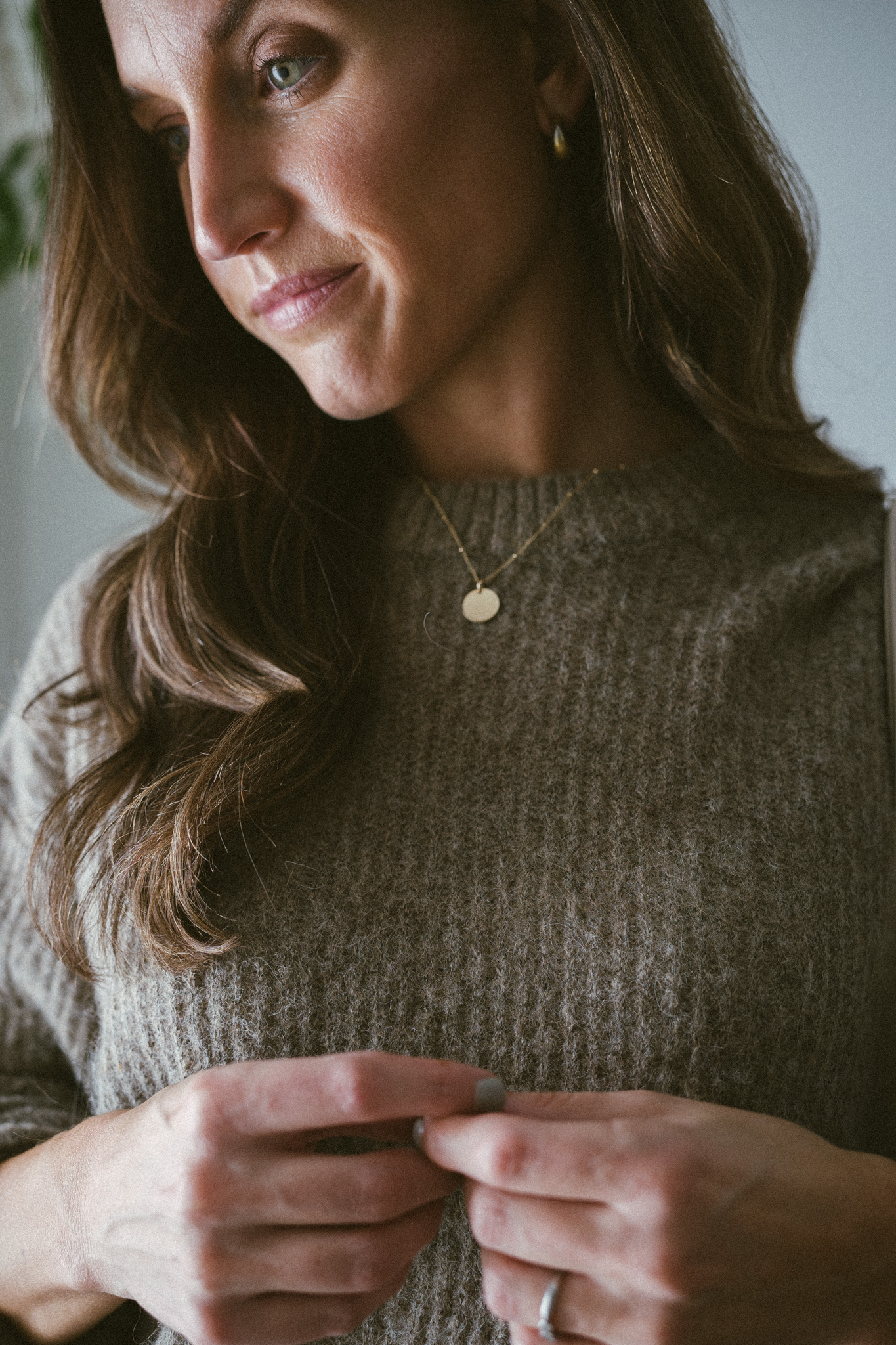ashley wearing a taupe oversized sweater, black pants, and bone colored boots with laces with a woven bone colored bag and black sunglasses