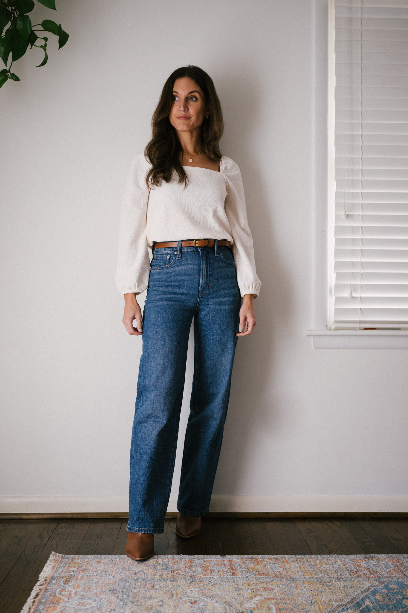 daily look featuring a white puff sleeve top, wide leg jeans with a brown belt, brown heeled ankle boots, and a gray shoulder bag