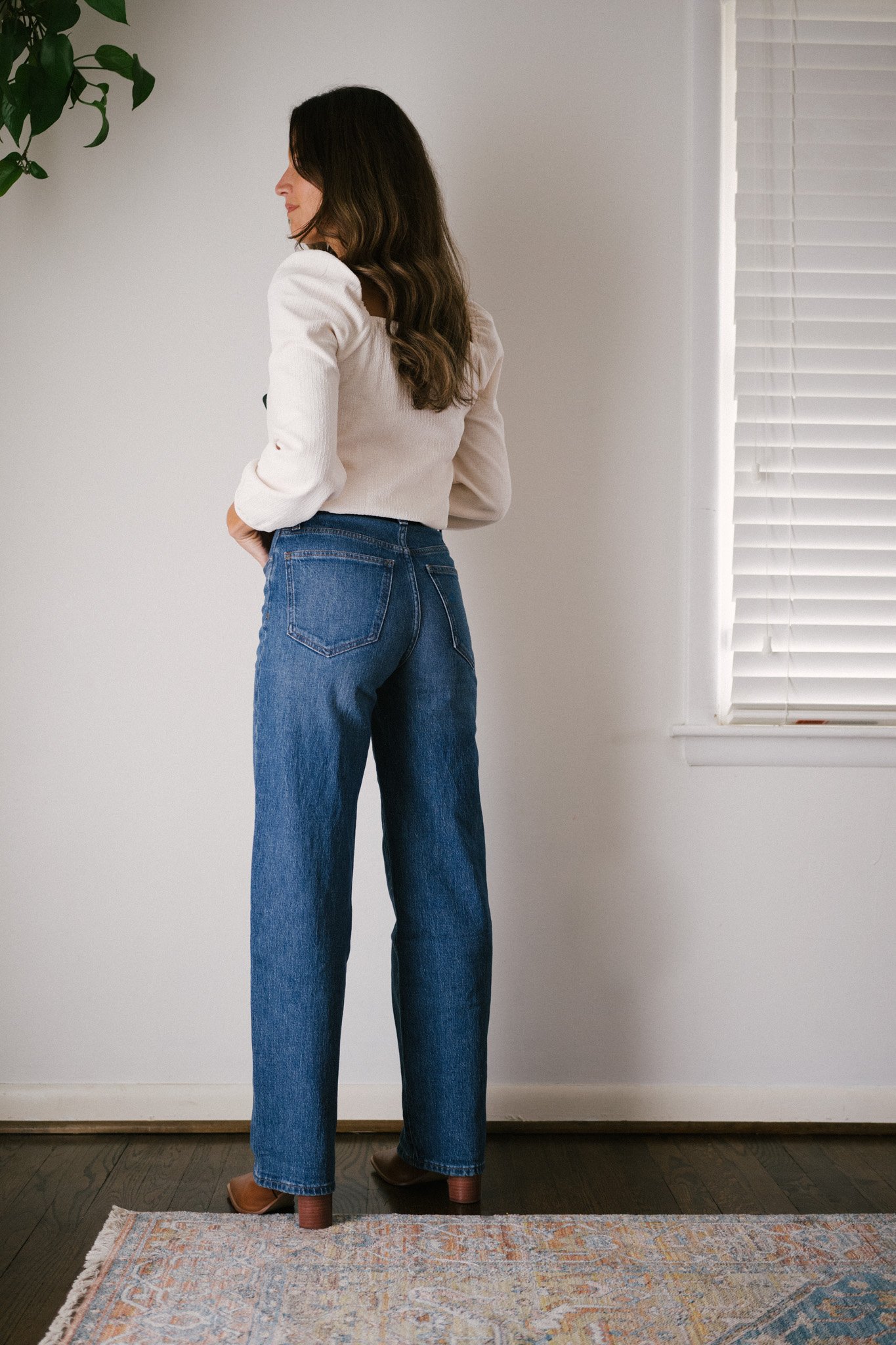 daily look featuring a white puff sleeve top, wide leg jeans with a brown belt, brown heeled ankle boots, and a gray shoulder bag