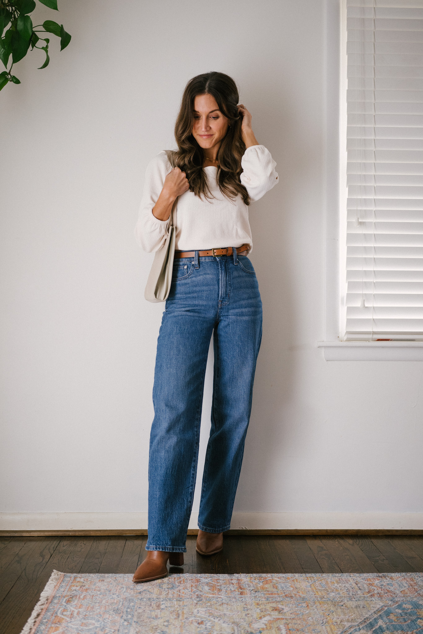 daily look featuring a white puff sleeve top, wide leg jeans with a brown belt, brown heeled ankle boots, and a gray shoulder bag