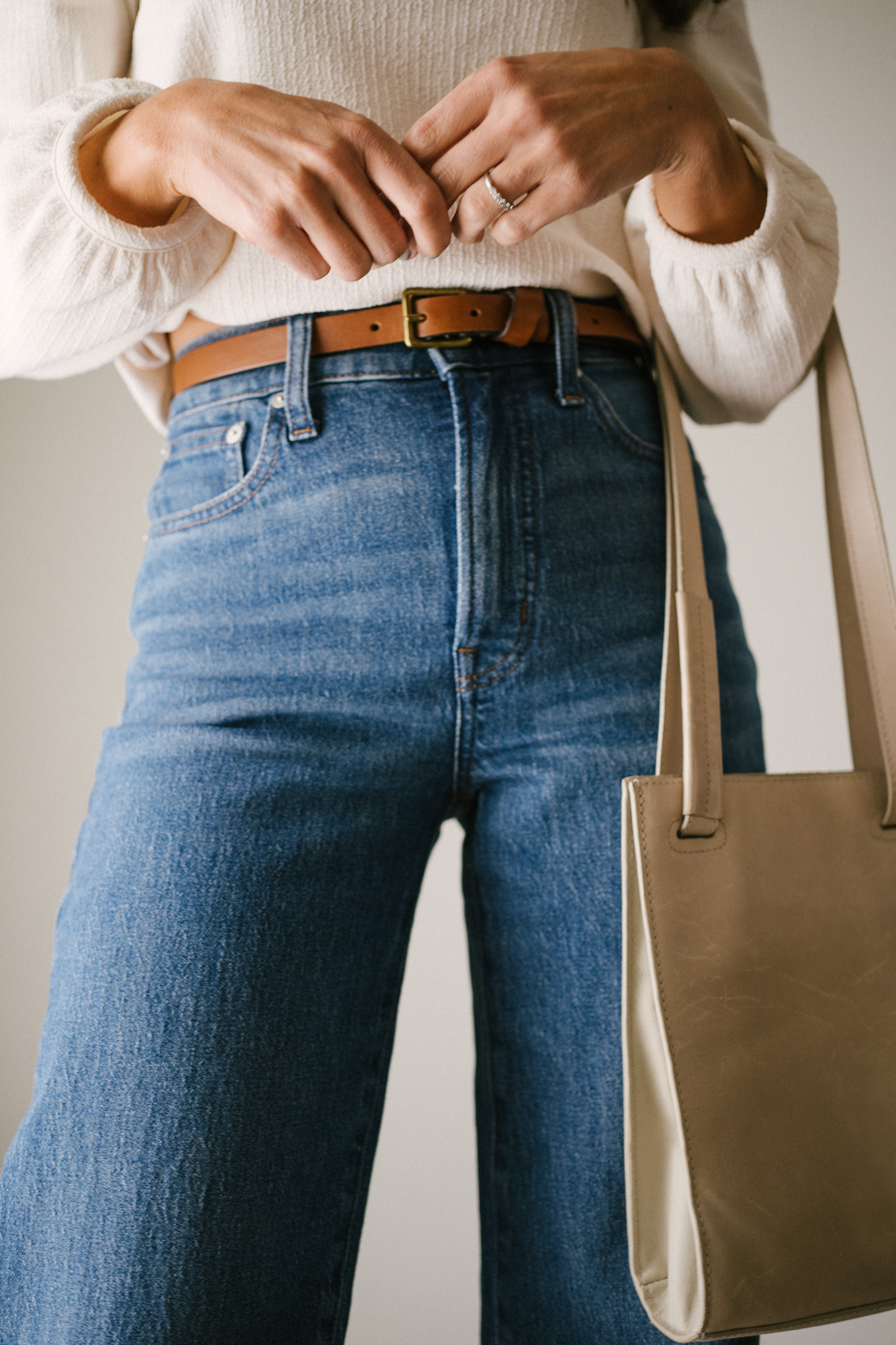 daily look featuring a white puff sleeve top, wide leg jeans with a brown belt, brown heeled ankle boots, and a gray shoulder bag