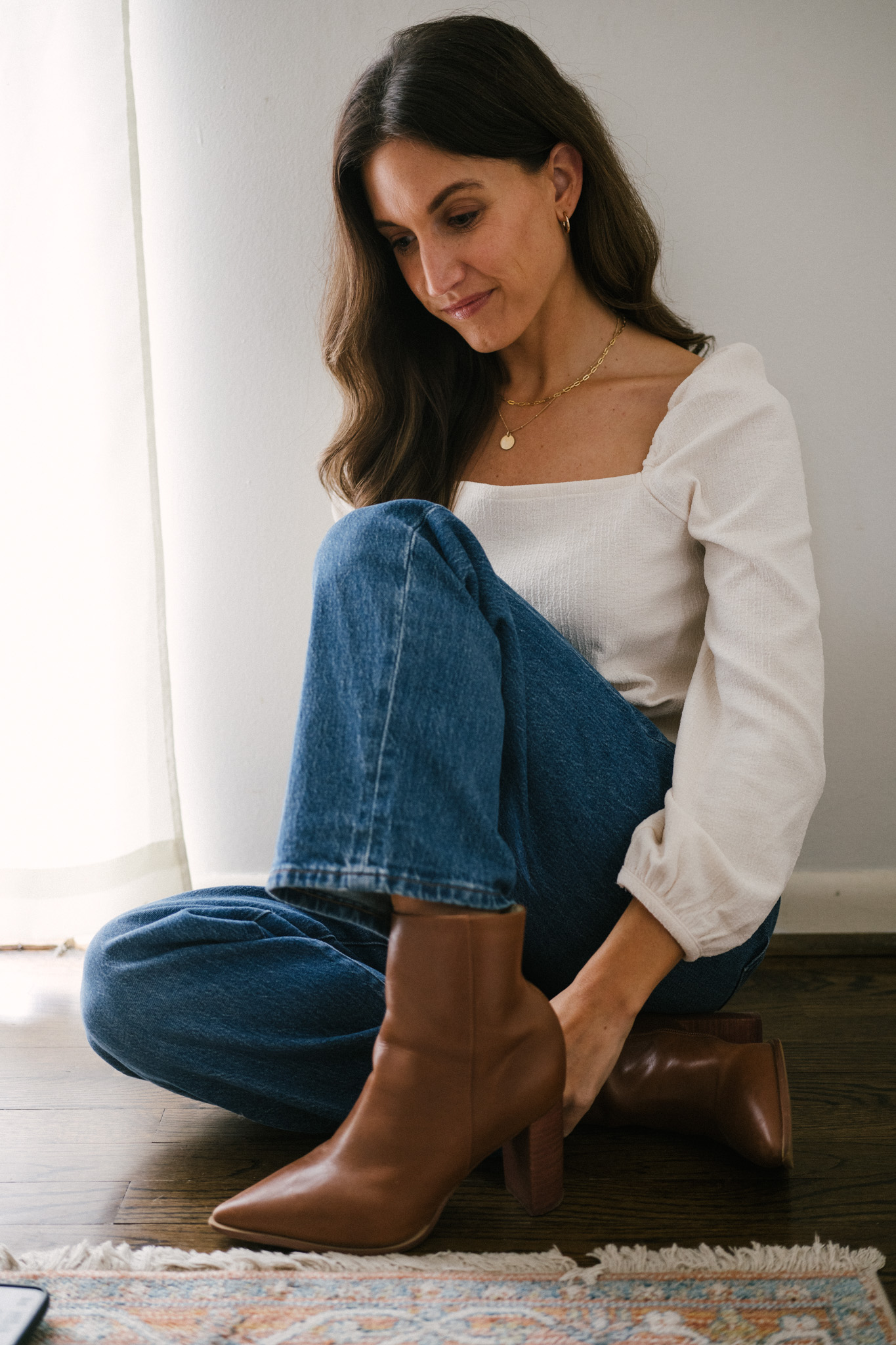 daily look featuring a white puff sleeve top, wide leg jeans with a brown belt, brown heeled ankle boots, and a gray shoulder bag