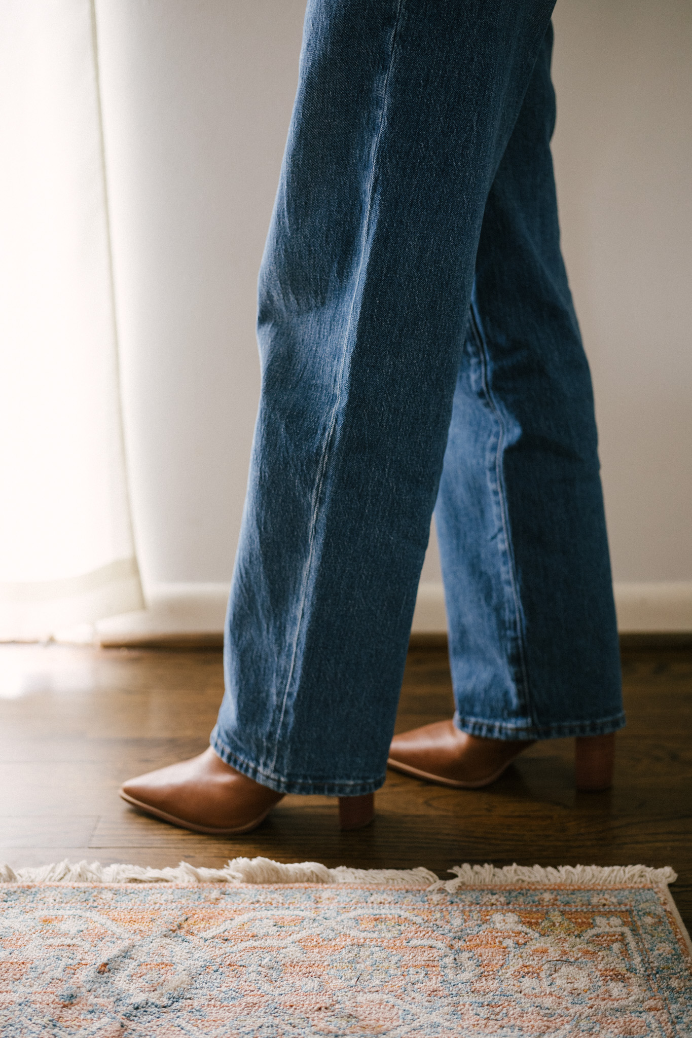 daily look featuring a white puff sleeve top, wide leg jeans with a brown belt, brown heeled ankle boots, and a gray shoulder bag