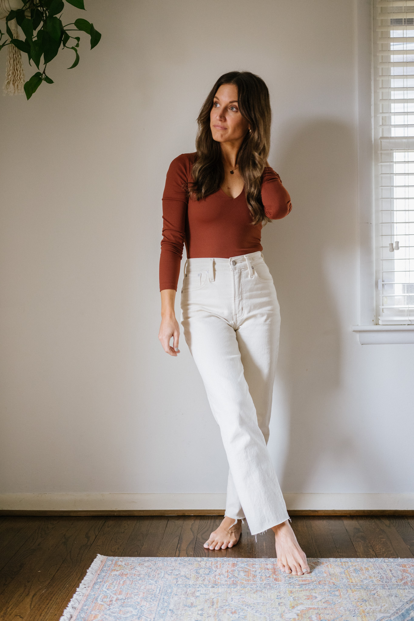 ashley wearing a reddish brown bodysuit and white jeans