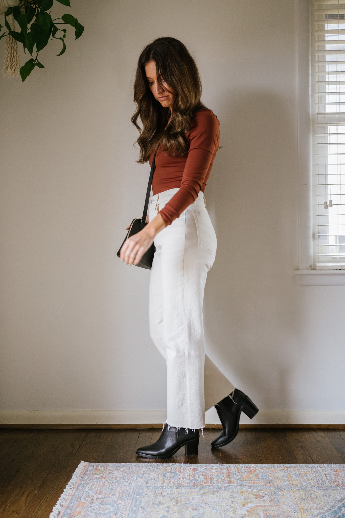 fall outfit with a reddish brown bodysuit, white denim, and black ankle boots