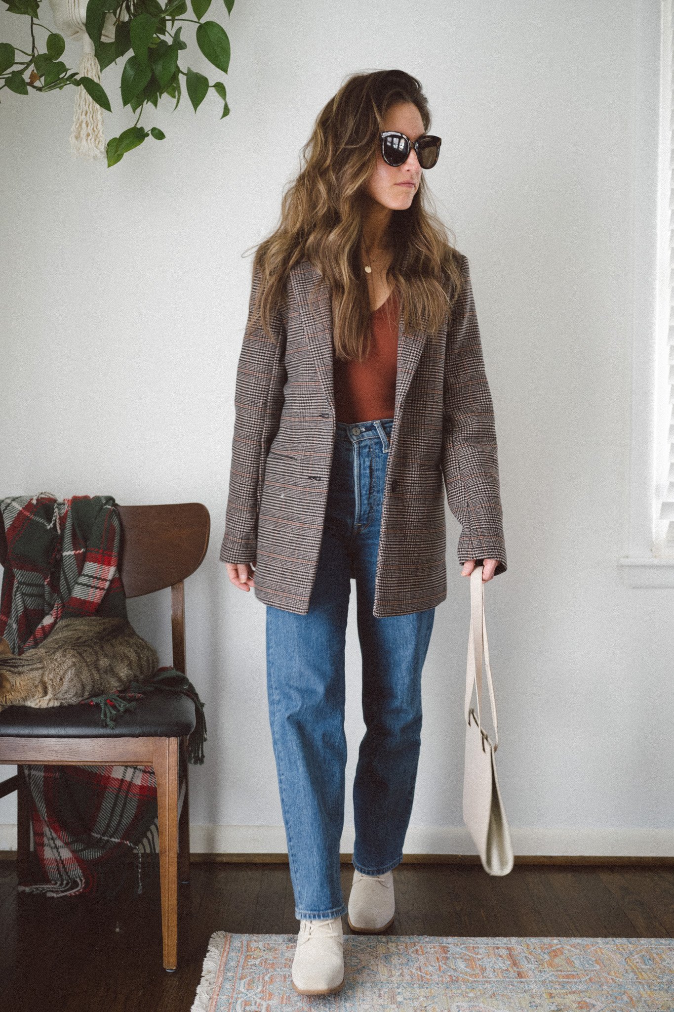 casual chic winter outfit with a brown bodysuit, plaid blazer coat, straight denim, and gray ankle boots