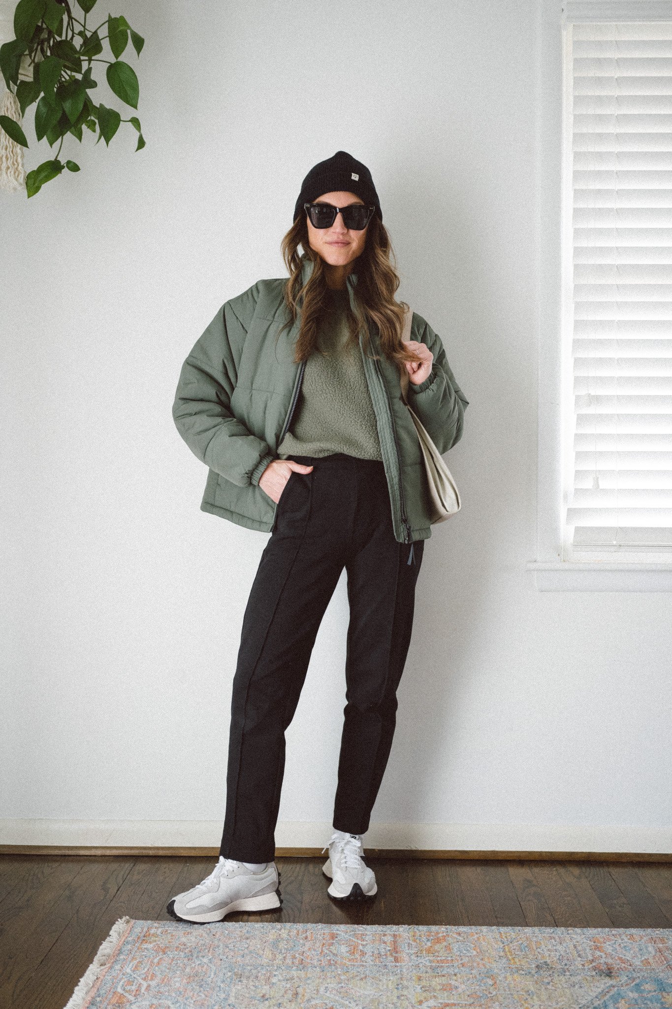 casual winter outfit with a green fleece sweatshirt, green puffer jacket, black pants, and casual sneakers