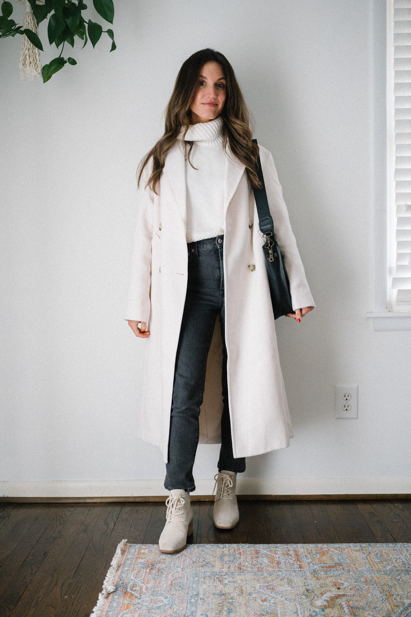 casual chic winter outfit with a white turtleneck sweater, ivory oversized coat, black denim, and light gray ankle boots