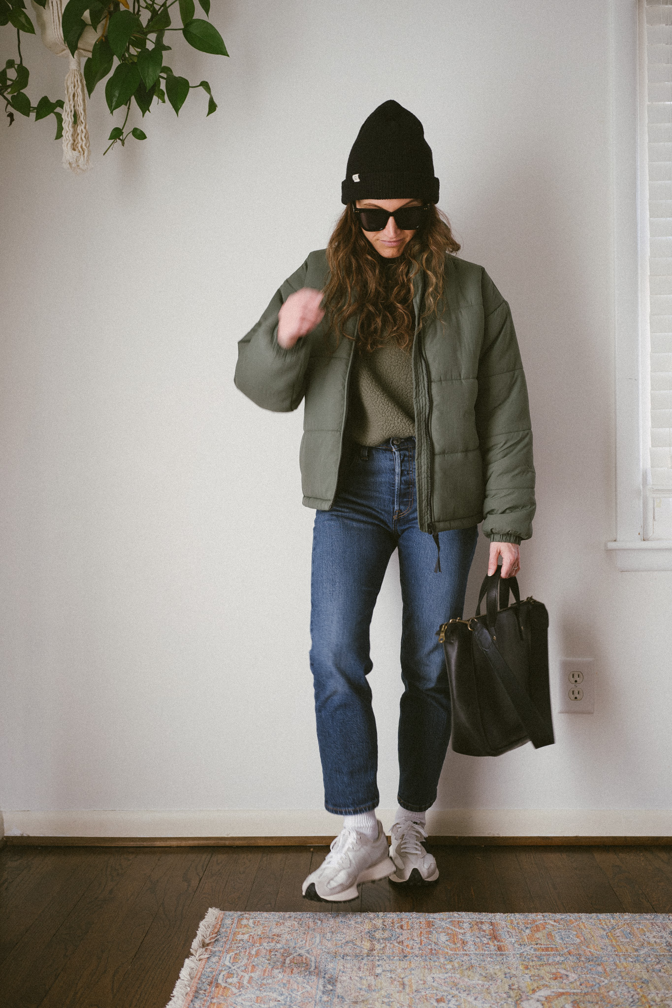 outfit from my winter capsule wardrobe with a green sweatshirt, green puffer jacket, dark wash denim, and casual sneakers