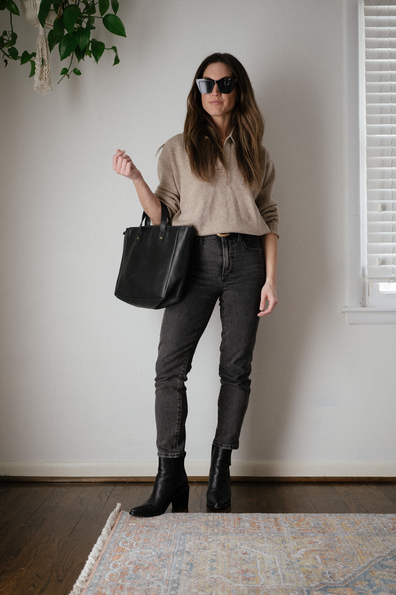 winter capsule wardrobe outfit with a taupe polo sweater, black denim, and black ankle boots