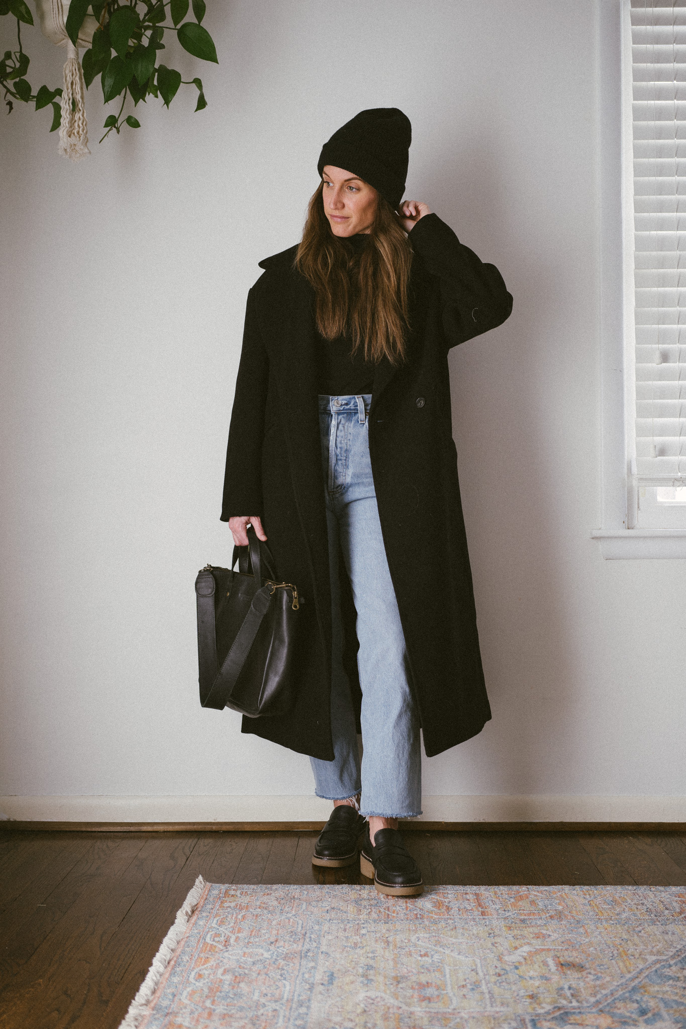 outfit from my winter capsule wardrobe with a black turtleneck, light wash straight denim, black loafers and a black oversized coat