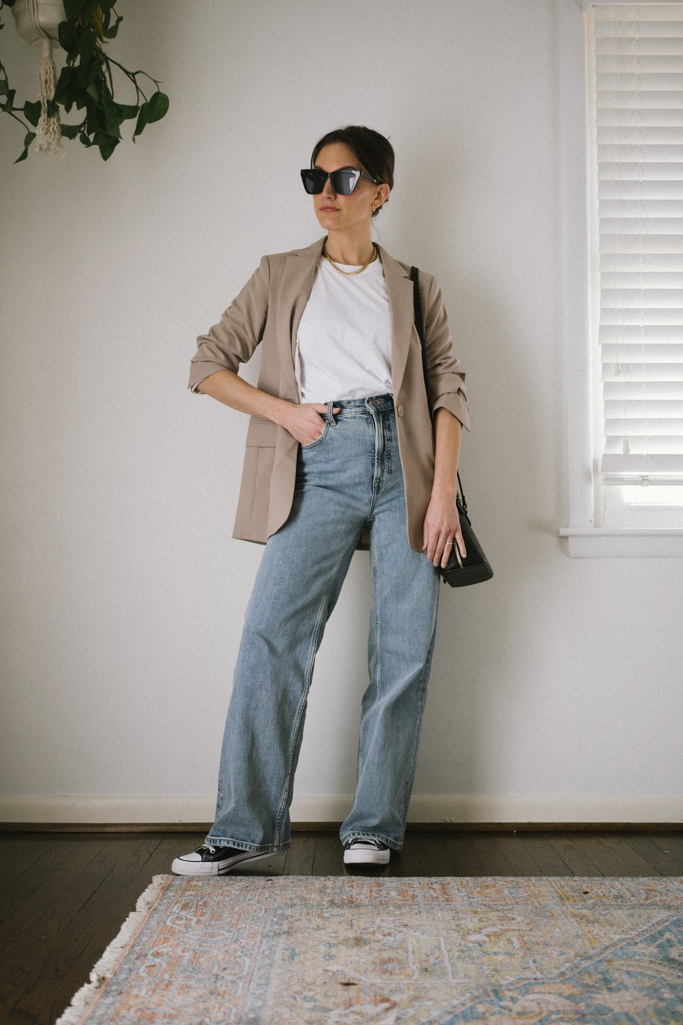 minimalist outfit with a white tee, taupe blazer, wide leg denim, and black high top Converse