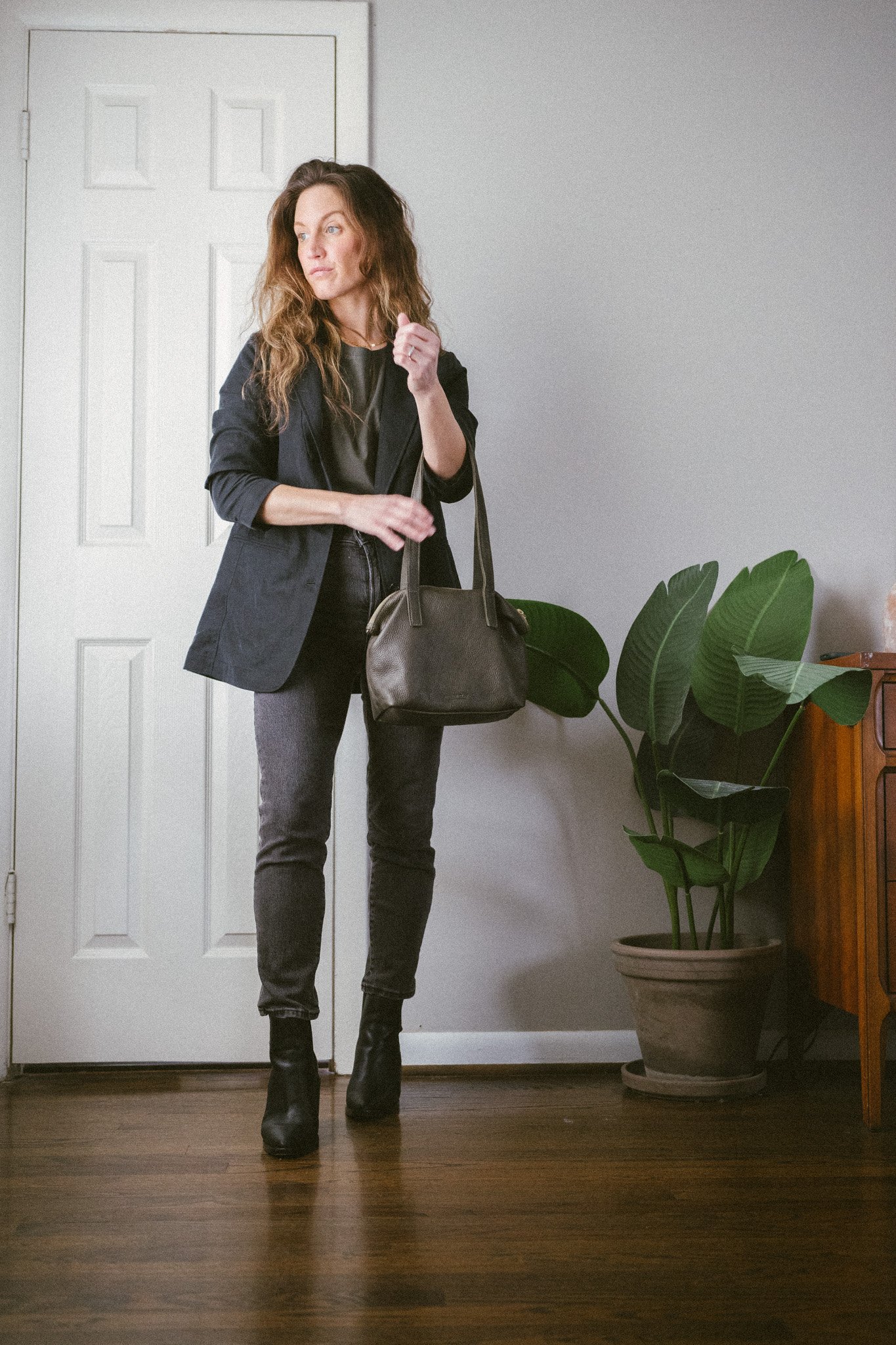 early spring outfit with a green tee, black blazer, washed black denim, and black boots