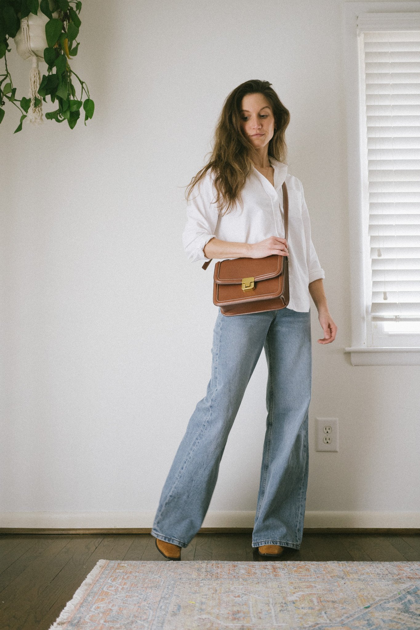minimalist outfit with a white button down, wide leg denim, and brown heeled booties