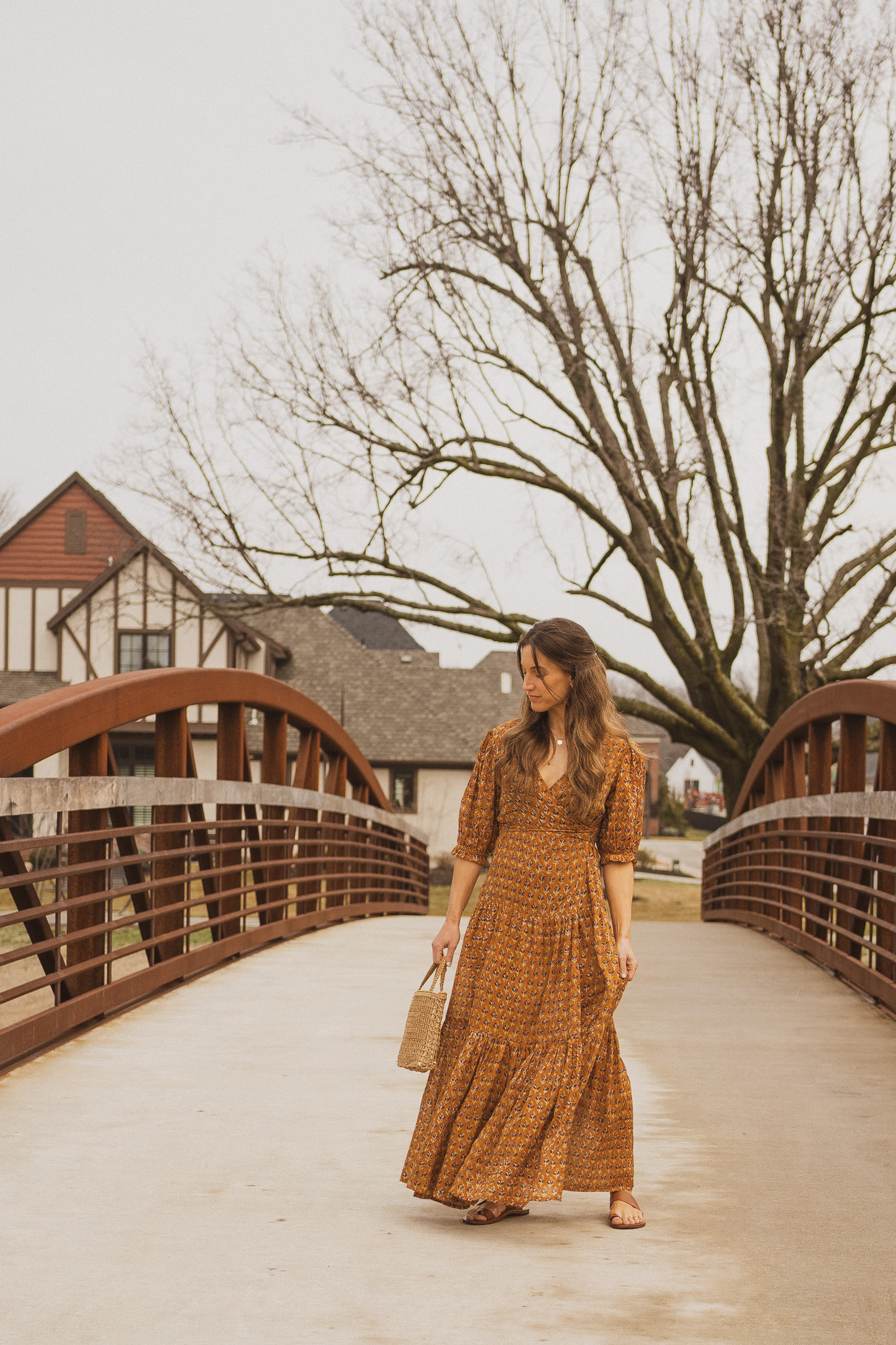 ashley wearing a spring maxi dress in and standing on a bridge