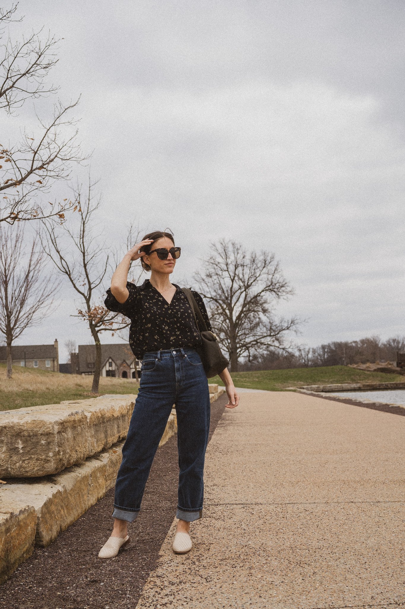 spring outfit idea with a black floral blouse, dark was denim, and bone colored woven mules