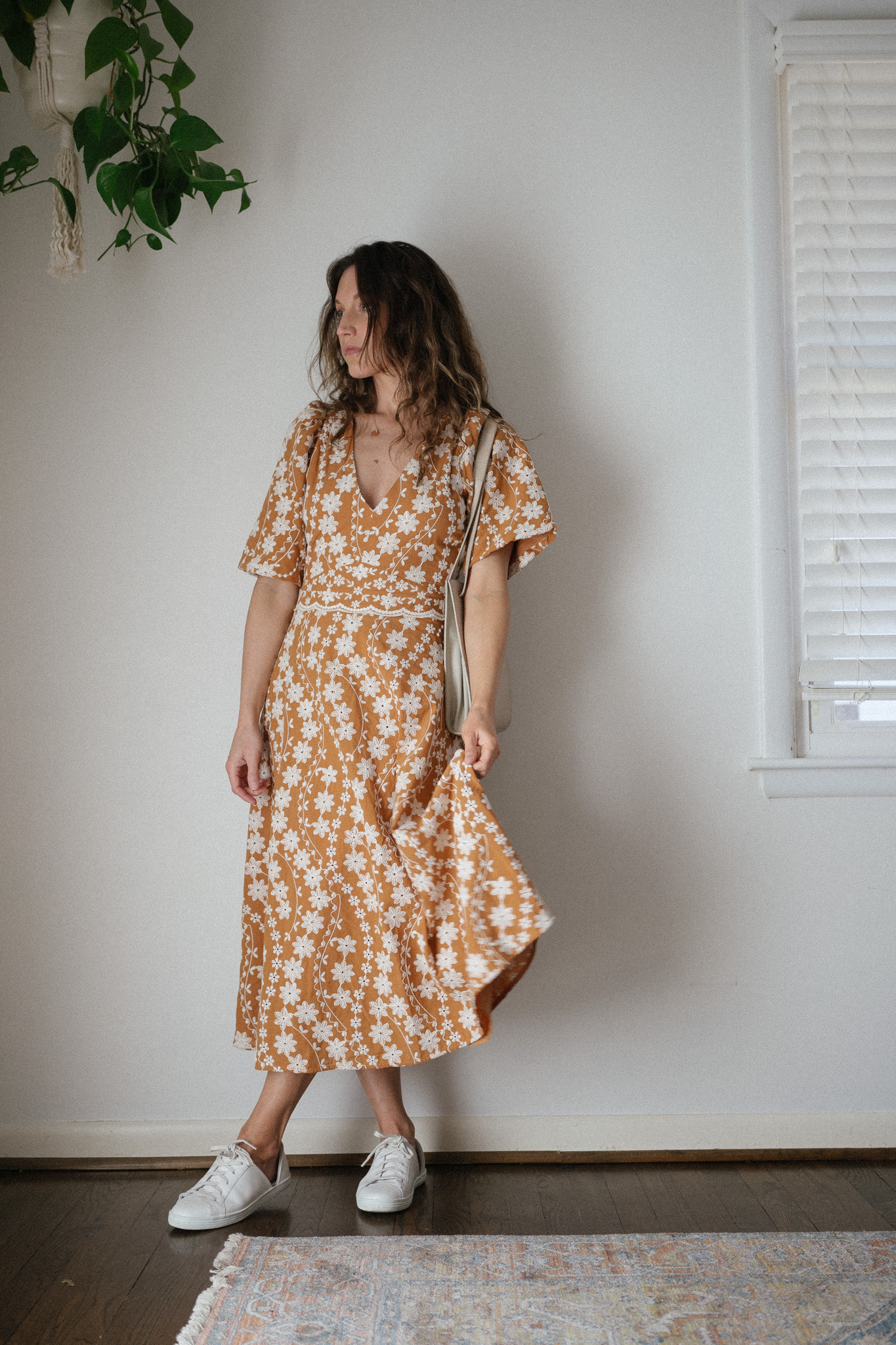 spring outfit idea with a floral mustard midi dress and white sneakers