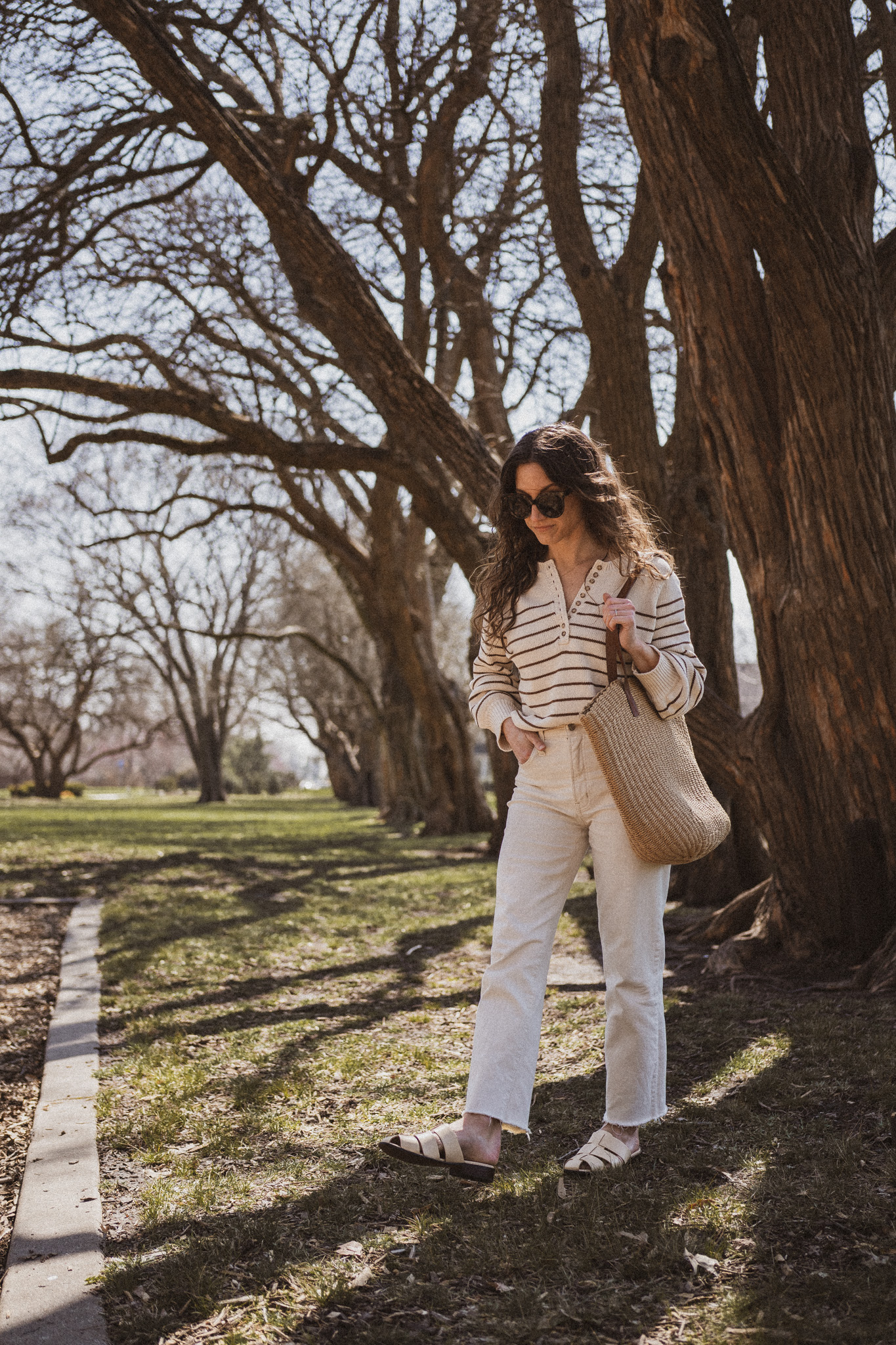 neutral spring outfit idea with a striped sweater, white denim, and cream colored mules