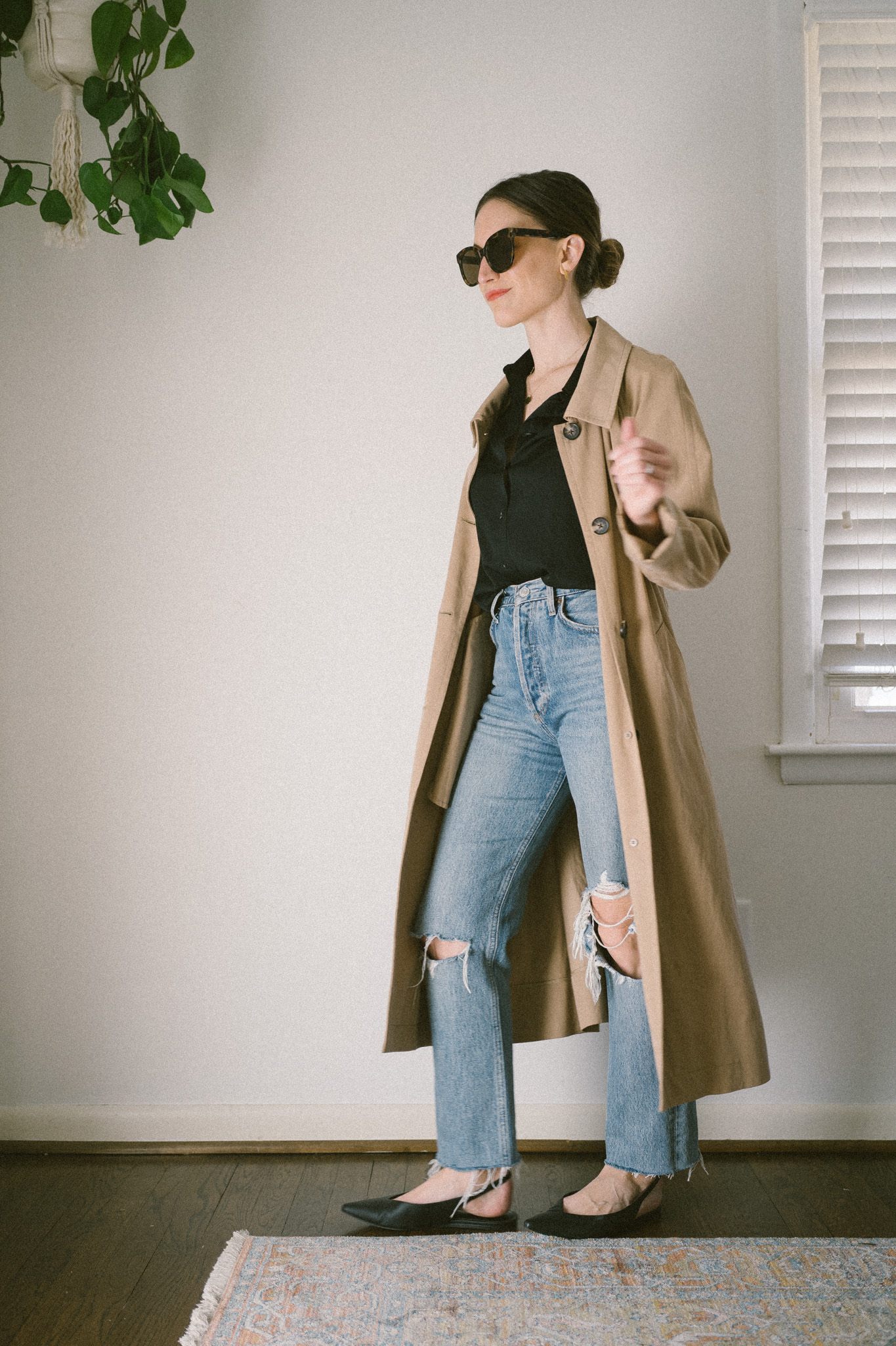 spring outfit idea with a black silk button down, distressed denim, a tan trench coat and black slingback flats