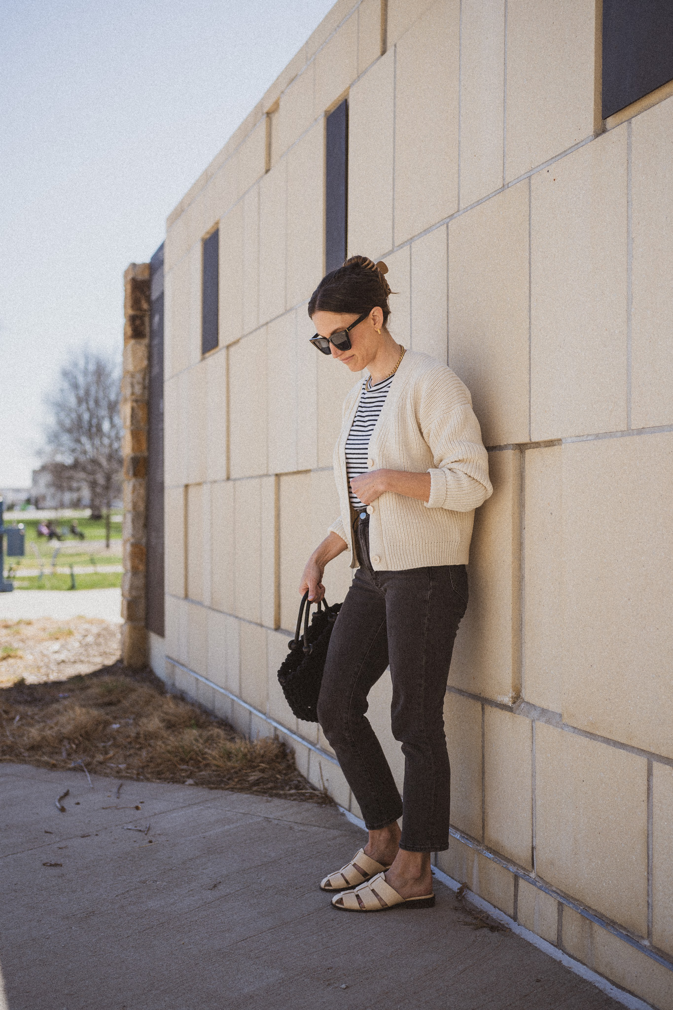 casual spring outfit idea with a striped tee, cream colored cropped cardigan, washed black denim, and cream colored fisherman mules