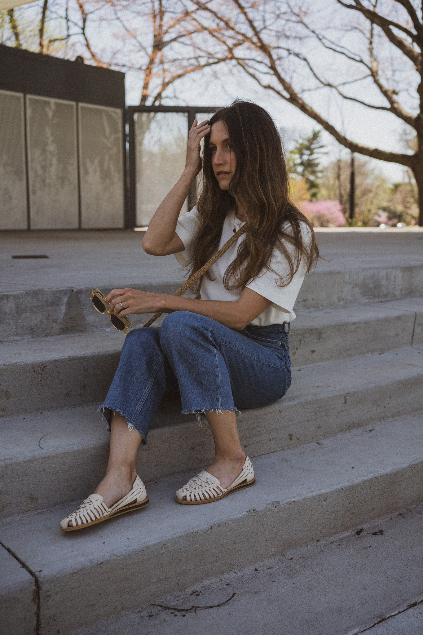 spring outfit with a white tee, medium wash denim, and white huarache sandals
